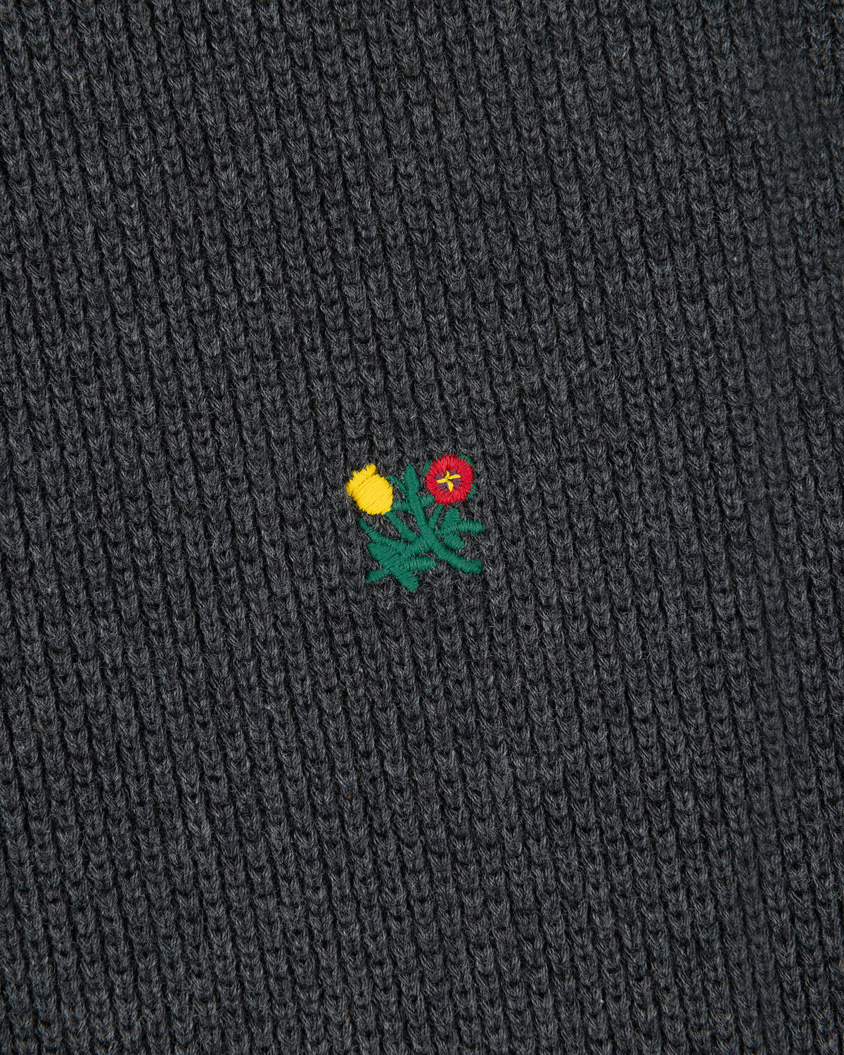 Close-up of Crest Piqué Half-Zip Pullover’s dark ribbed fabric with an embroidered yellow and red flower.