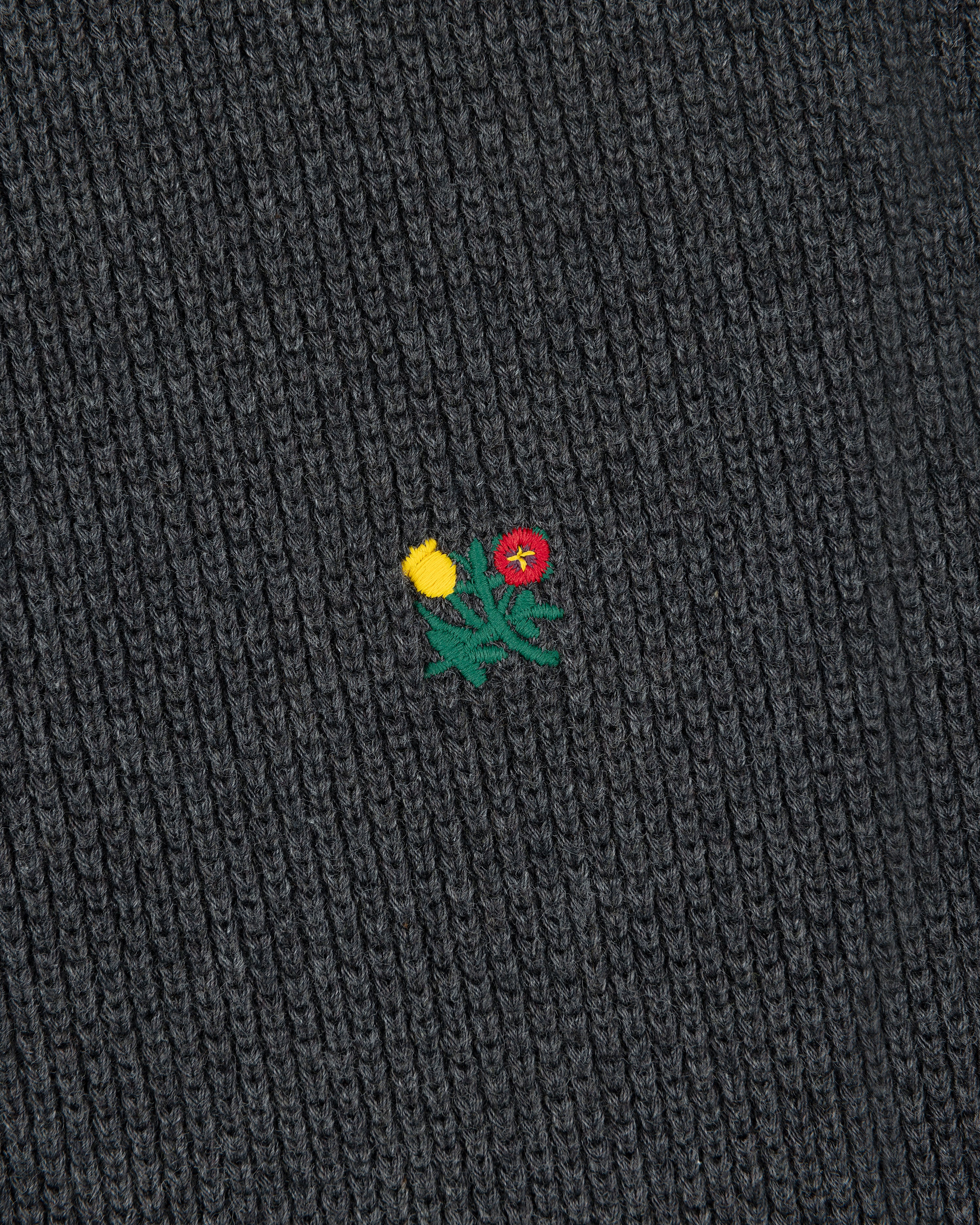 Close-up of Crest Piqué Half-Zip Pullover’s dark ribbed fabric with an embroidered yellow and red flower.