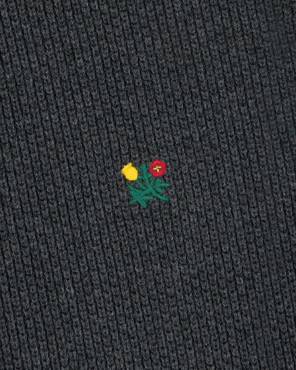 Close-up of Crest Piqué Half-Zip Pullover’s dark ribbed fabric with an embroidered yellow and red flower.