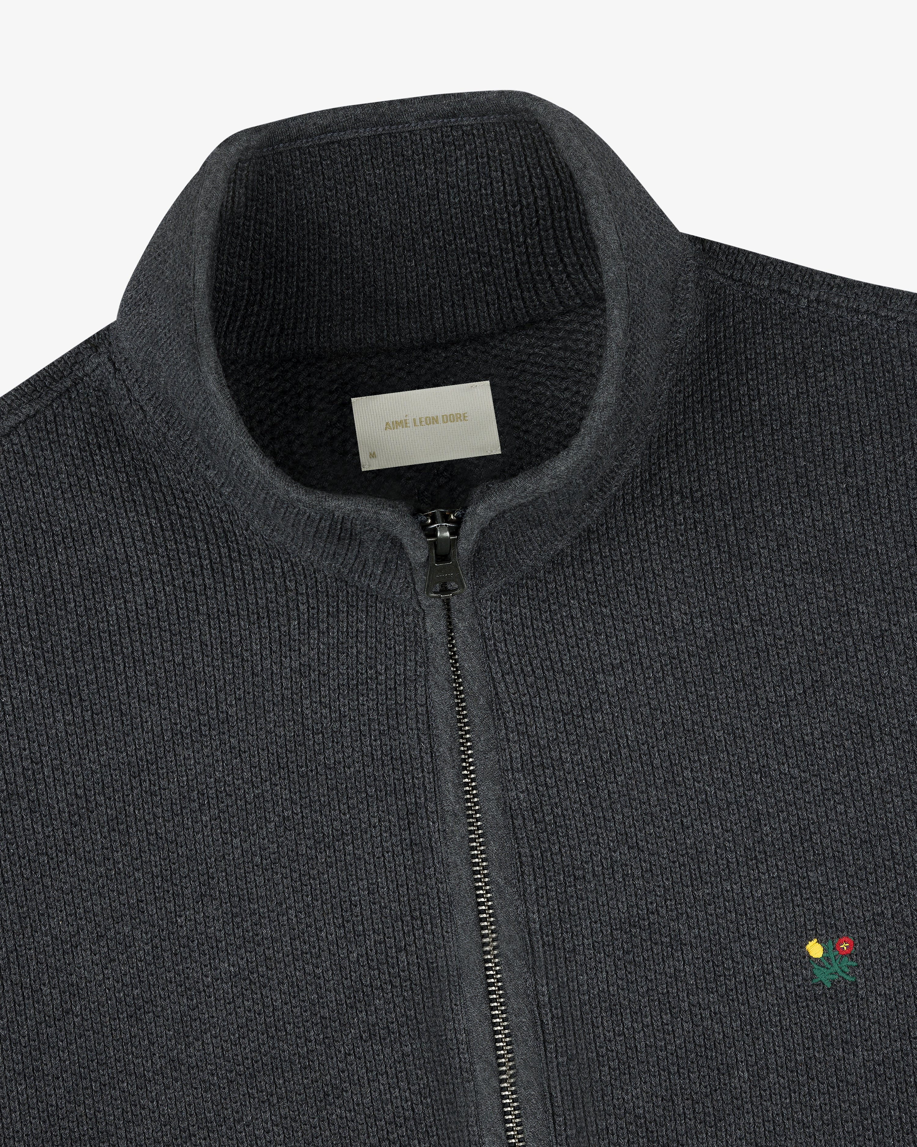 Crest Piqué Half-Zip Pullover in dark gray with ribbed texture, small embroidered flower, and visible collar label.