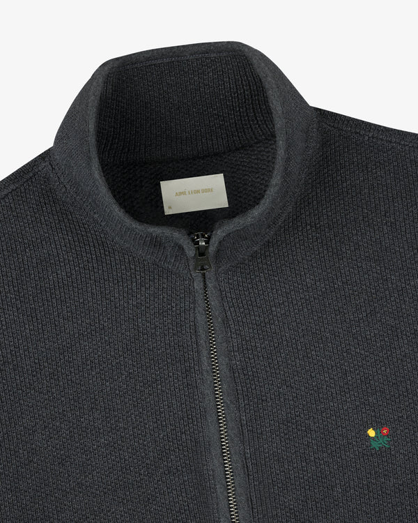 Crest Piqué Half-Zip Pullover in dark gray with ribbed texture, small embroidered flower, and visible collar label.
