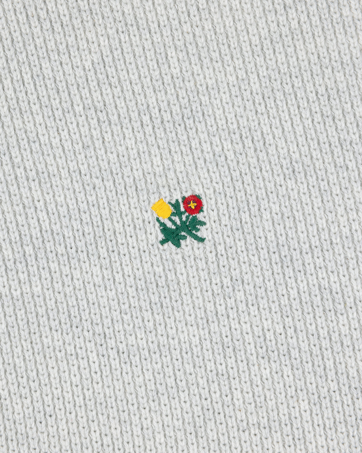 Small yellow and red embroidered flower on the light grey Crest Piqué Half-Zip Pullover.