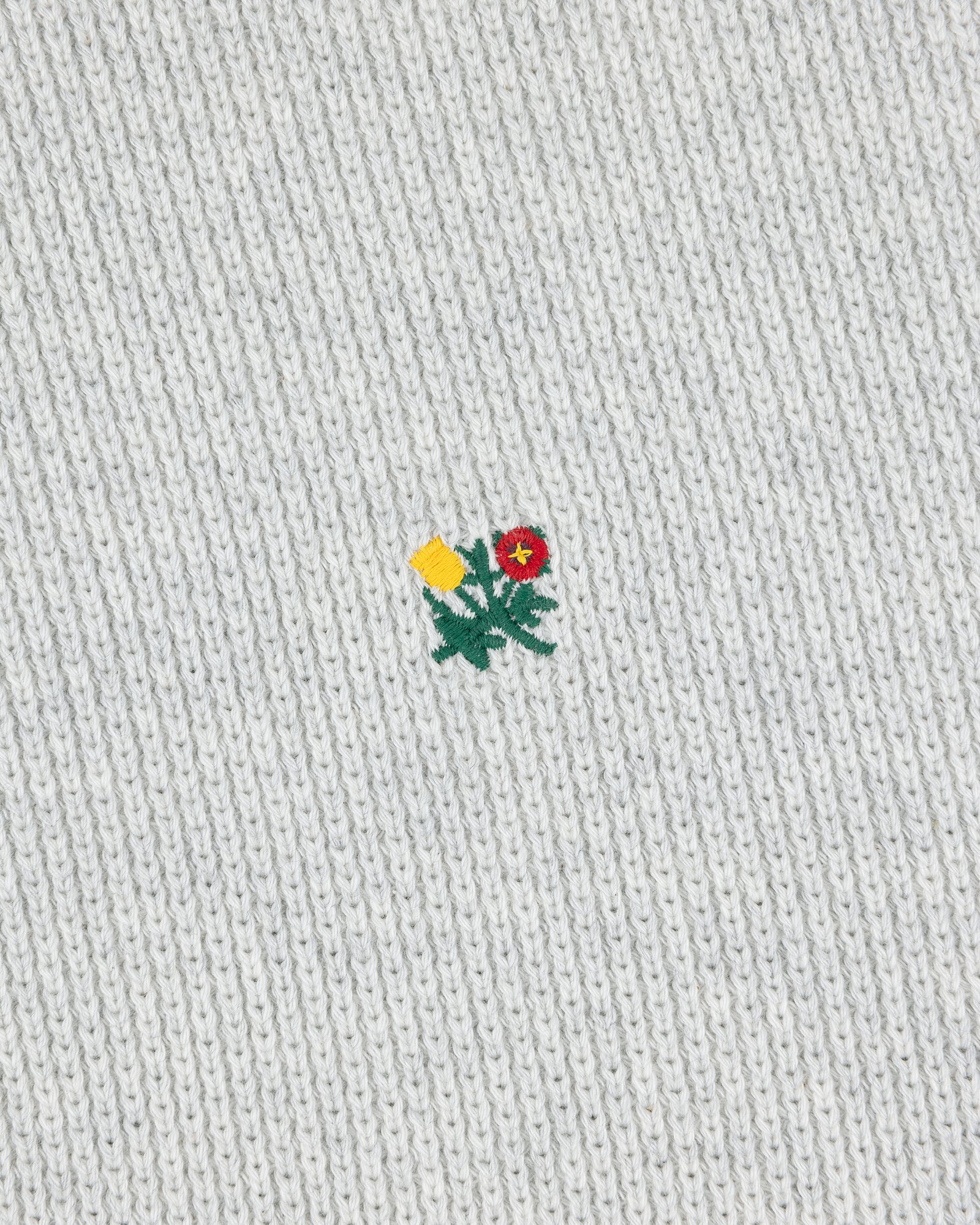 Small yellow and red embroidered flower on the light grey Crest Piqué Half-Zip Pullover.