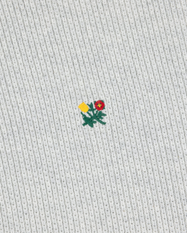 Small yellow and red embroidered flower on the light grey Crest Piqué Half-Zip Pullover.