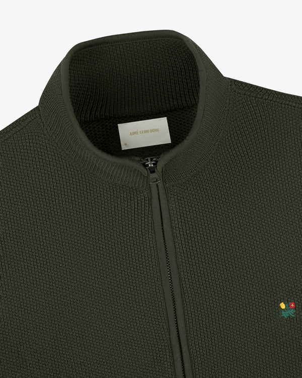 Close-up of the Crest Piqué Half-Zip Pullover in dark green with small flower embroidery and a ribbed collar.