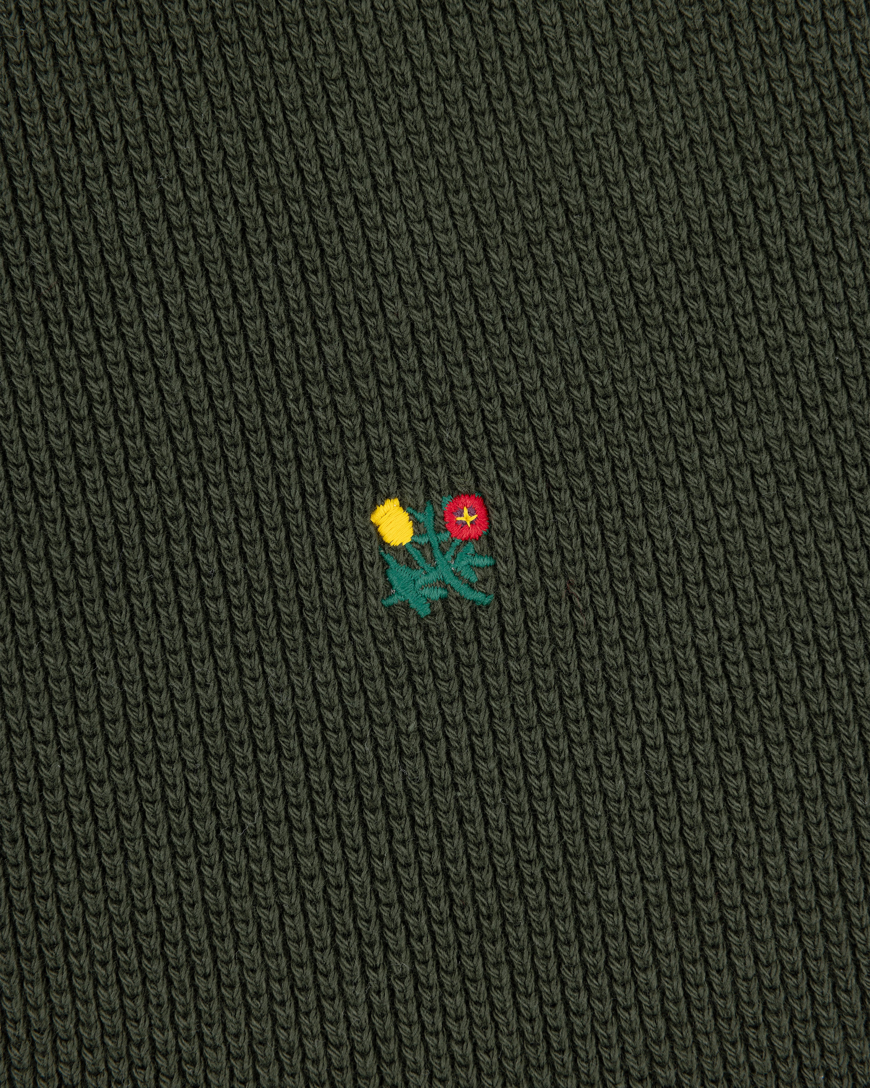 Dark green Crest Piqué Half-Zip Pullover with ribbed fabric and small embroidered yellow and red flowers in the center.