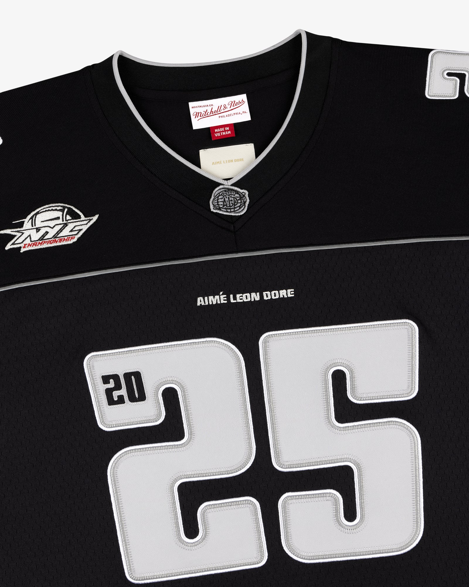 Black football jersey with large gray 25, ALD / Mitchell & Ness, and white logo patch near the shoulder.