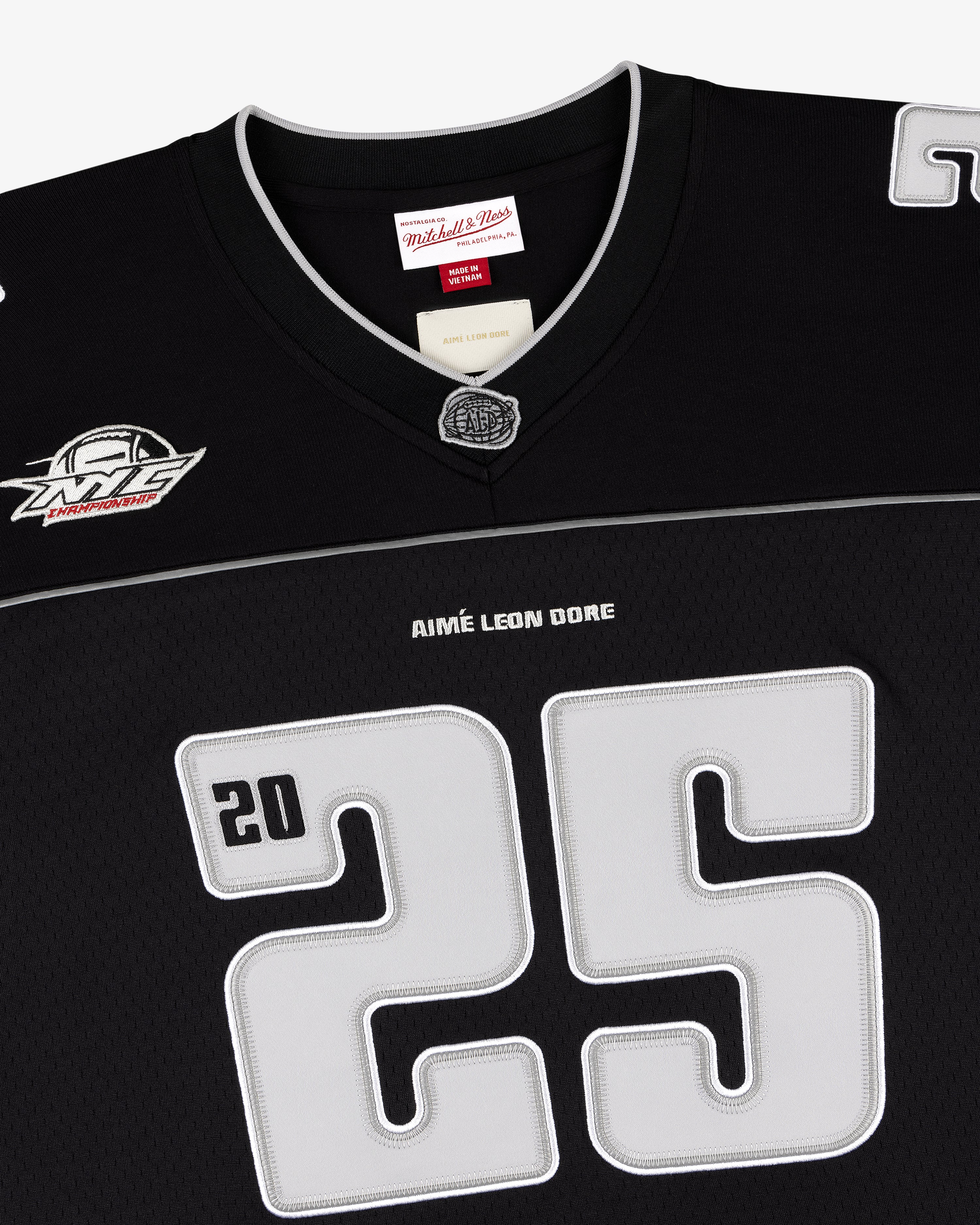 Black football jersey with large gray 25, ALD / Mitchell & Ness, and white logo patch near the shoulder.