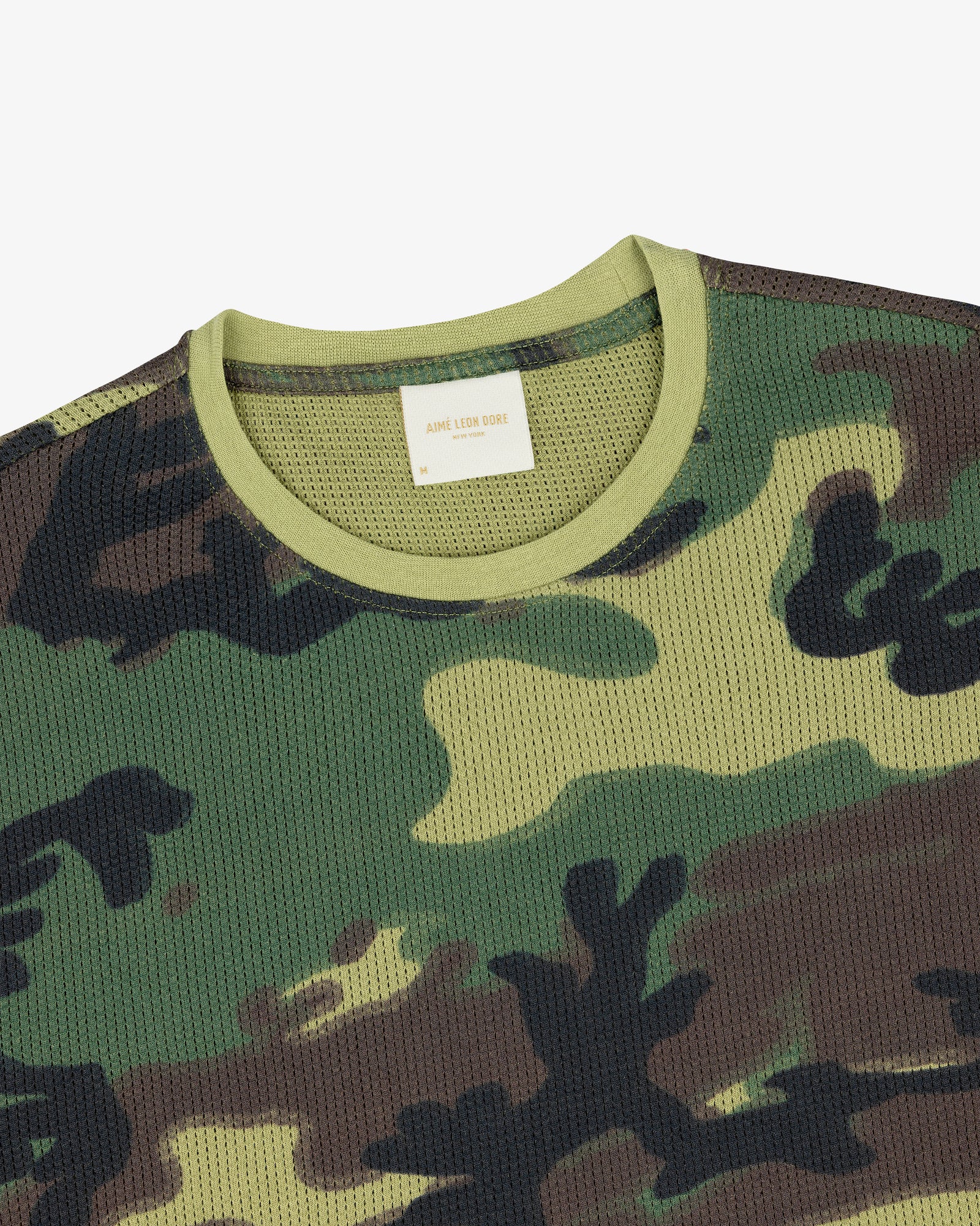 Close-up of the Printed Mesh Moto Tee featuring a green, brown, and black camo pattern with a light green collar.