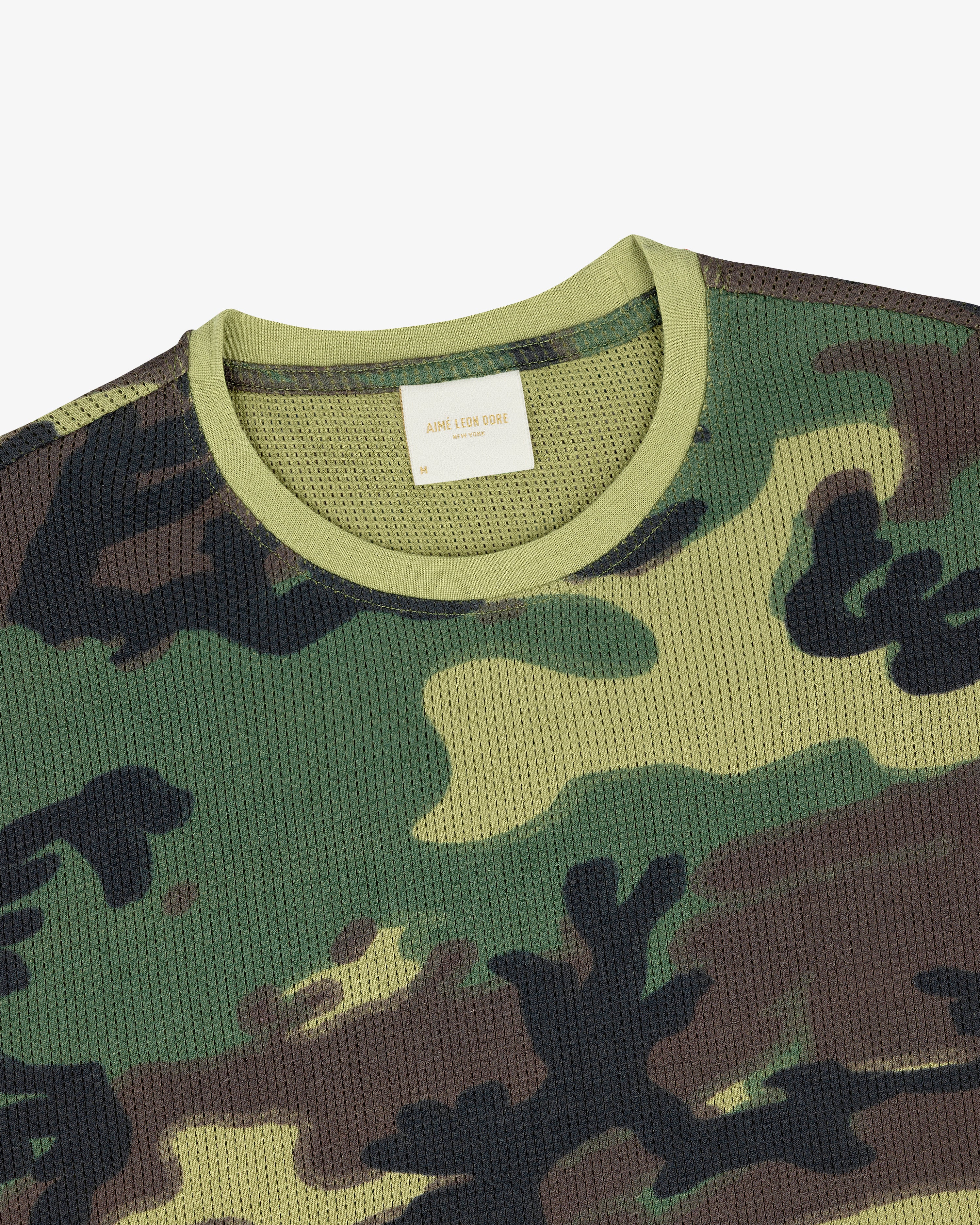 Close-up of the Printed Mesh Moto Tee featuring a green, brown, and black camo pattern with a light green collar.