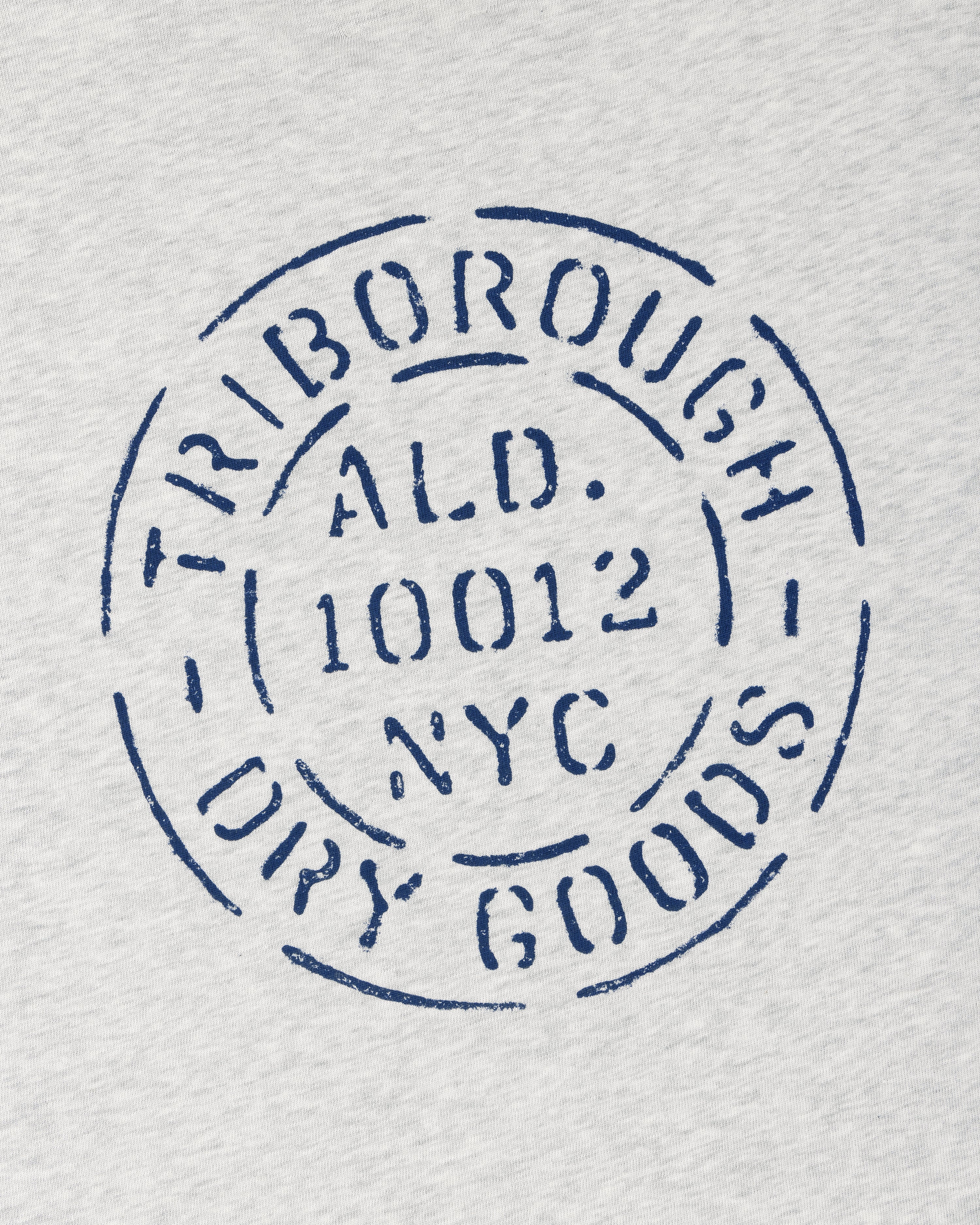 Circular blue “TRIBOROUGH DRY GOODS ALD. 10012 NYC” stamp on light gray Triborough Dry Goods Pocket Tee.