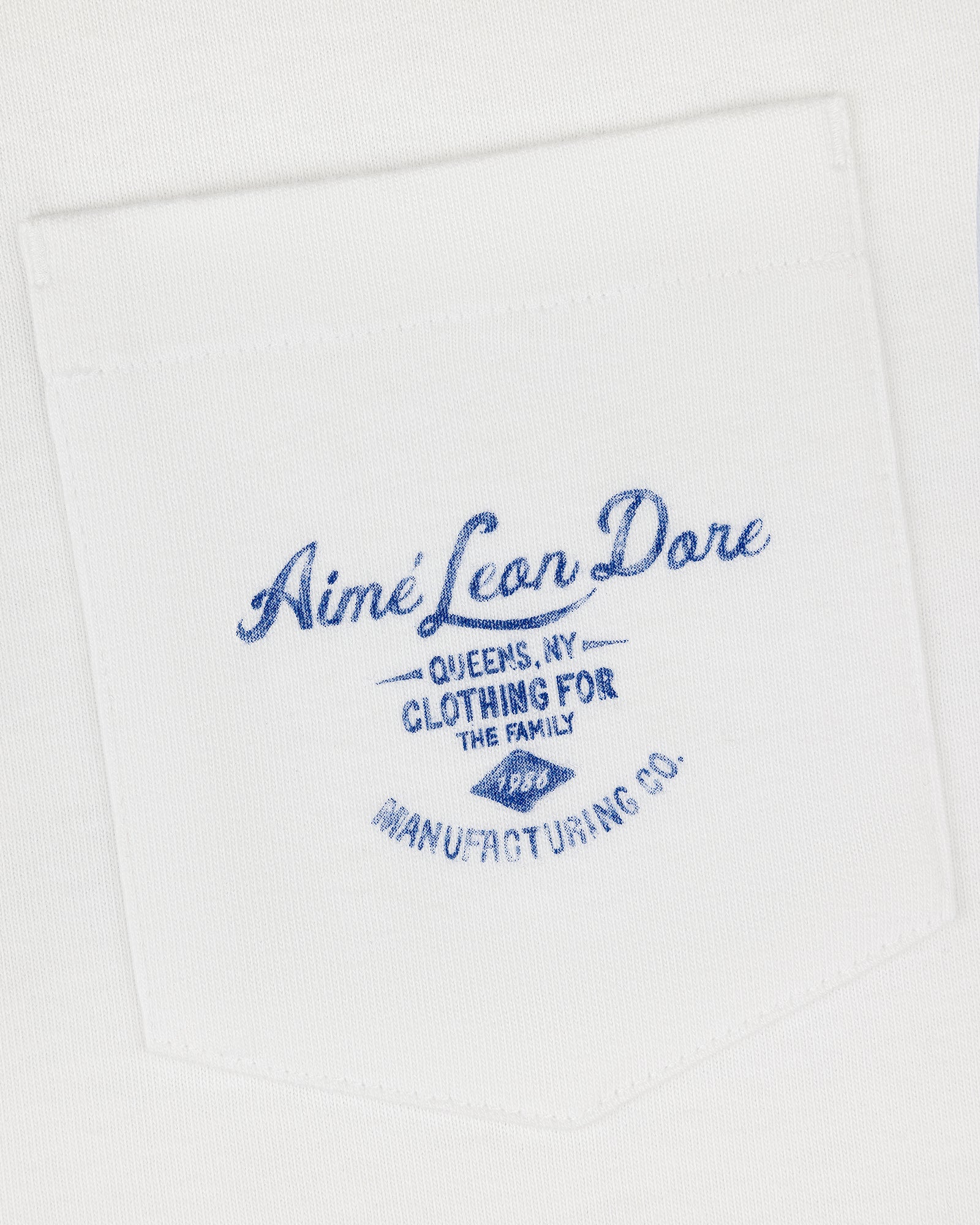 General Store Pocket Tee: White shirt pocket with blue text—Aimé Leon Dore, Queens, NY, Clothing for the Family.