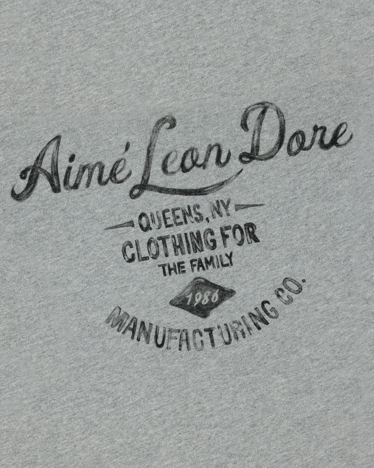 Gray General Store Pocket Tee with "Aimé Leon Dore Queens, NY Clothing for the Family 1980 Manufacturing Co." in black text.