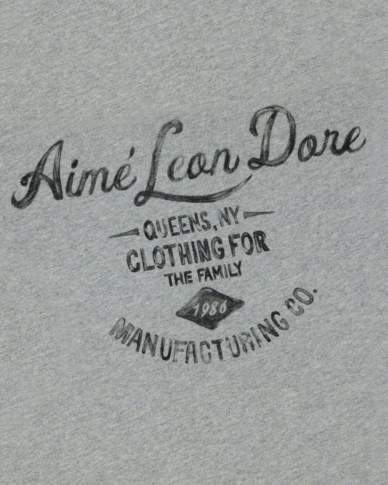 Gray General Store Pocket Tee with "Aimé Leon Dore Queens, NY Clothing for the Family 1980 Manufacturing Co." in black text.