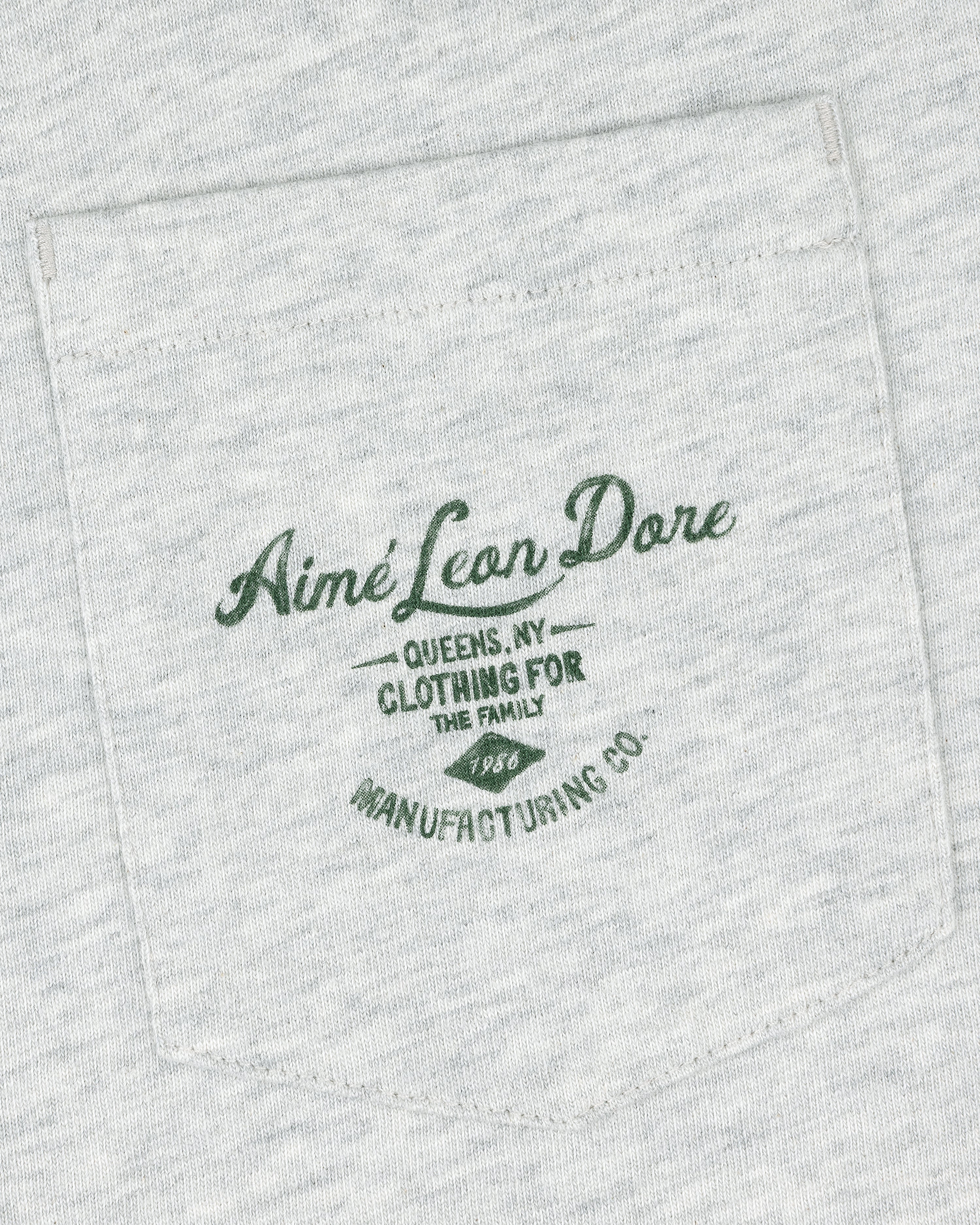 Light gray General Store Pocket Tee with dark green text: "Aimé Leon Dore Queens, NY Clothing For The Family 1986 Manufacturing Co.