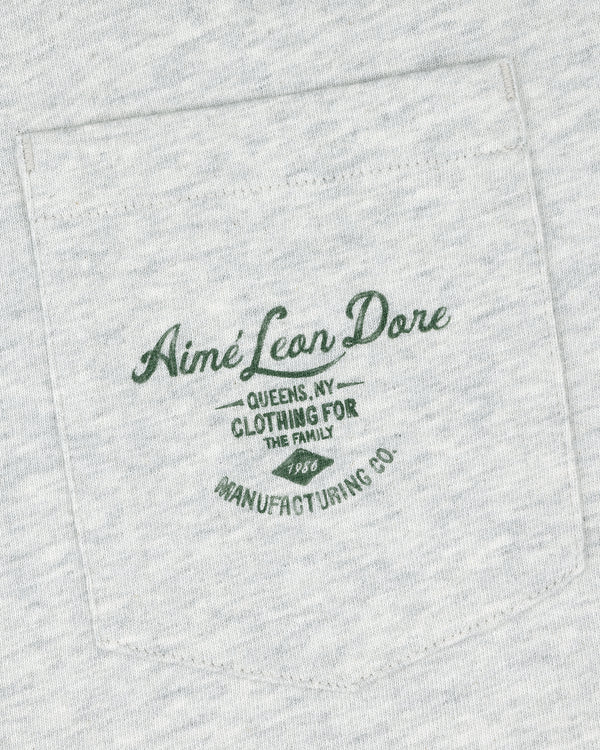 Light gray General Store Pocket Tee with dark green text: "Aimé Leon Dore Queens, NY Clothing For The Family 1986 Manufacturing Co.