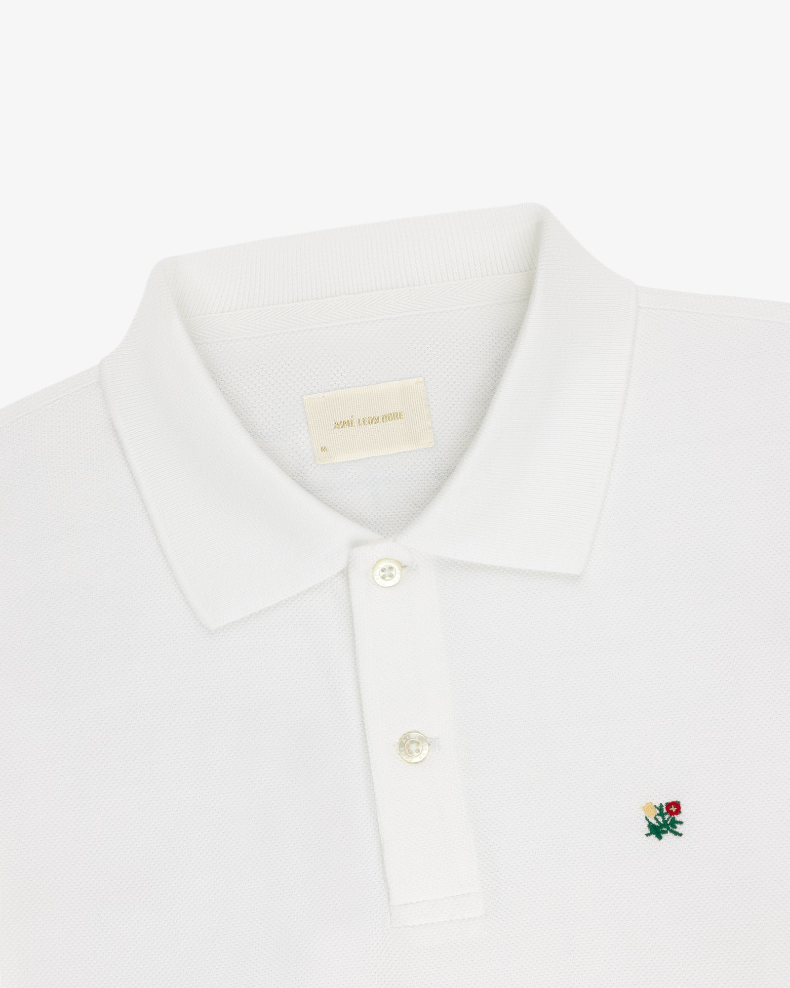 White Long-Sleeve Crest Piqué Polo with a collar, two buttons, and small embroidered rose logo on chest.