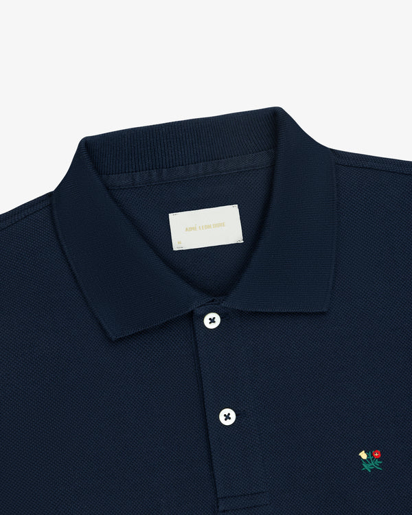 Long-Sleeve Crest Piqué Polo in navy blue with white buttons and a small flower chest embroidery, on white background.