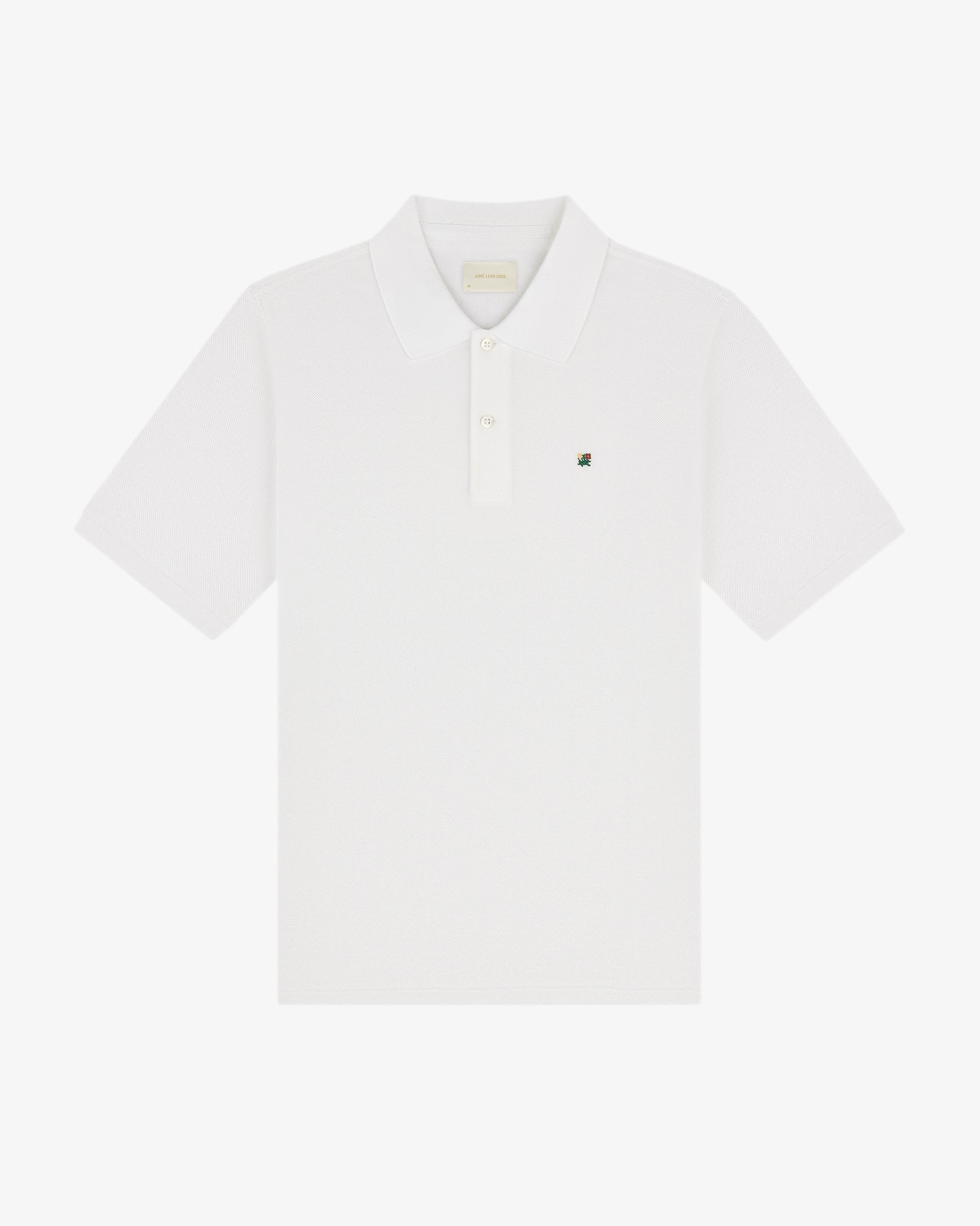 The Crest Piqué Polo is a white short-sleeve shirt with a collar and small embroidered logo on the left chest.