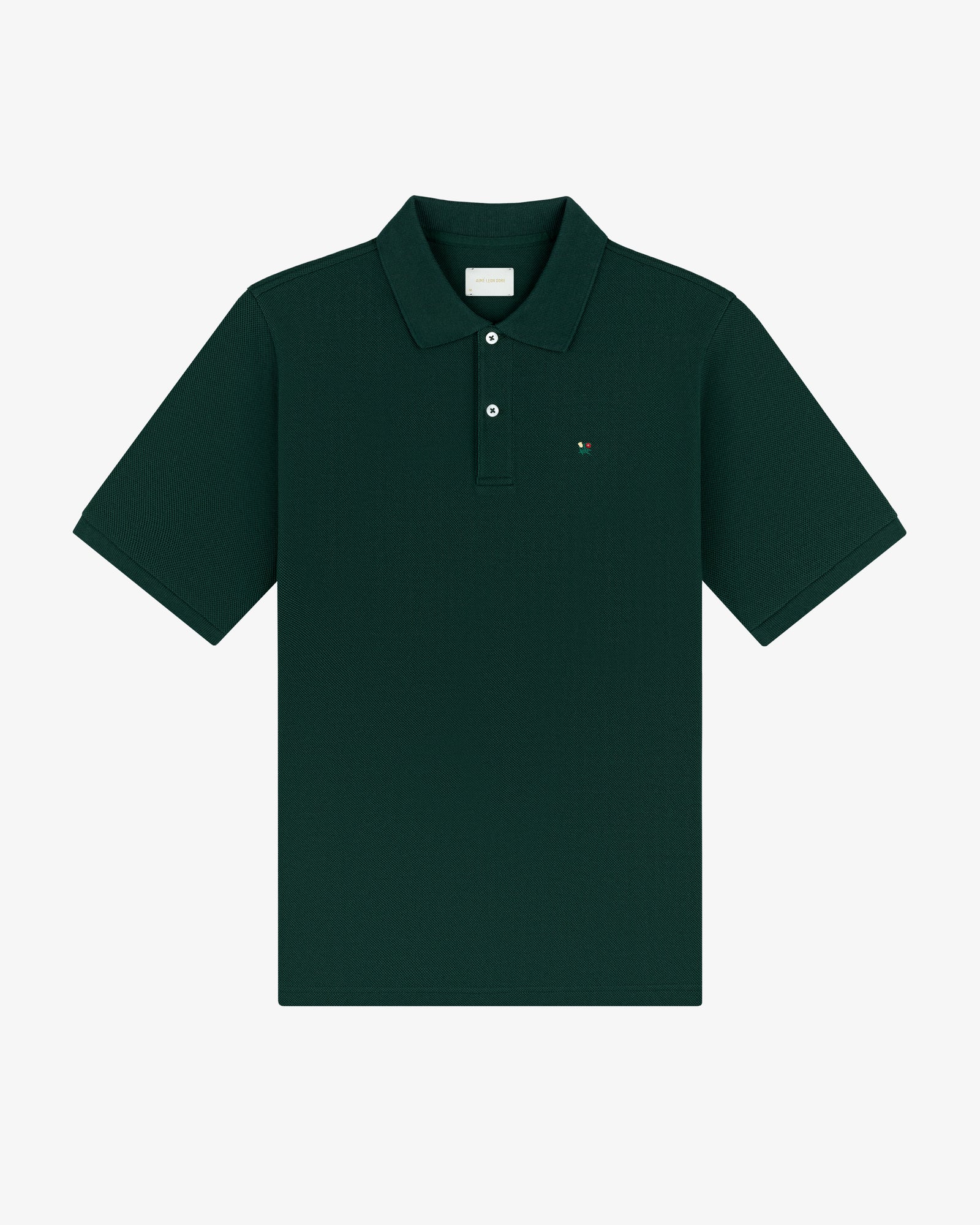 Crest Piqué Polo in dark green, short sleeves, collared with buttons, and a small chest logo, laid flat.