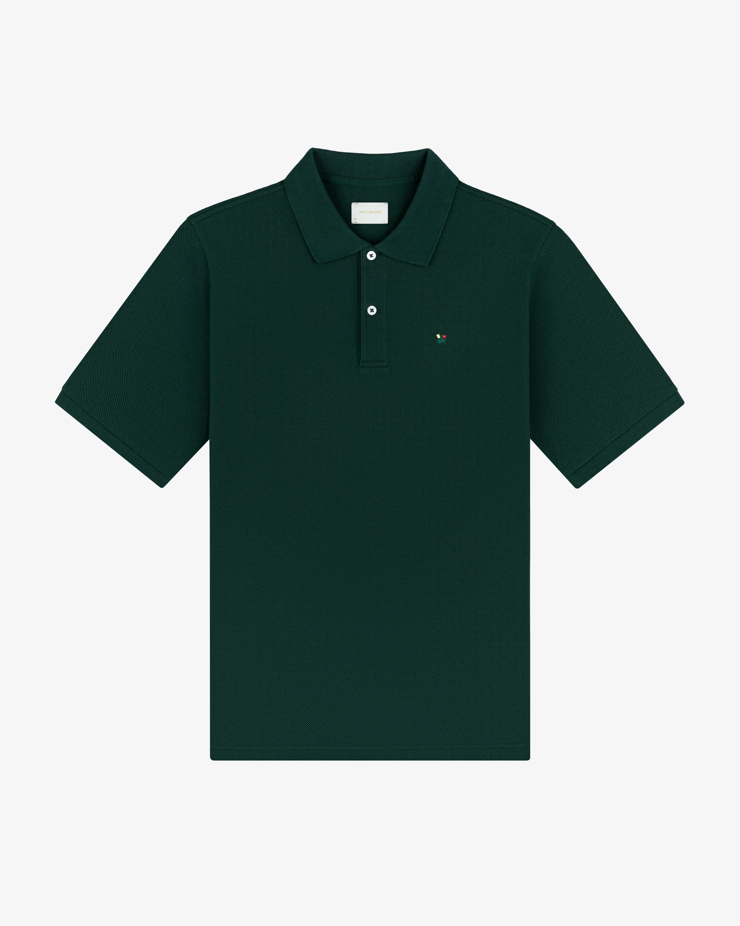 Crest Piqué Polo in dark green, short sleeves, collared with buttons, and a small chest logo, laid flat.