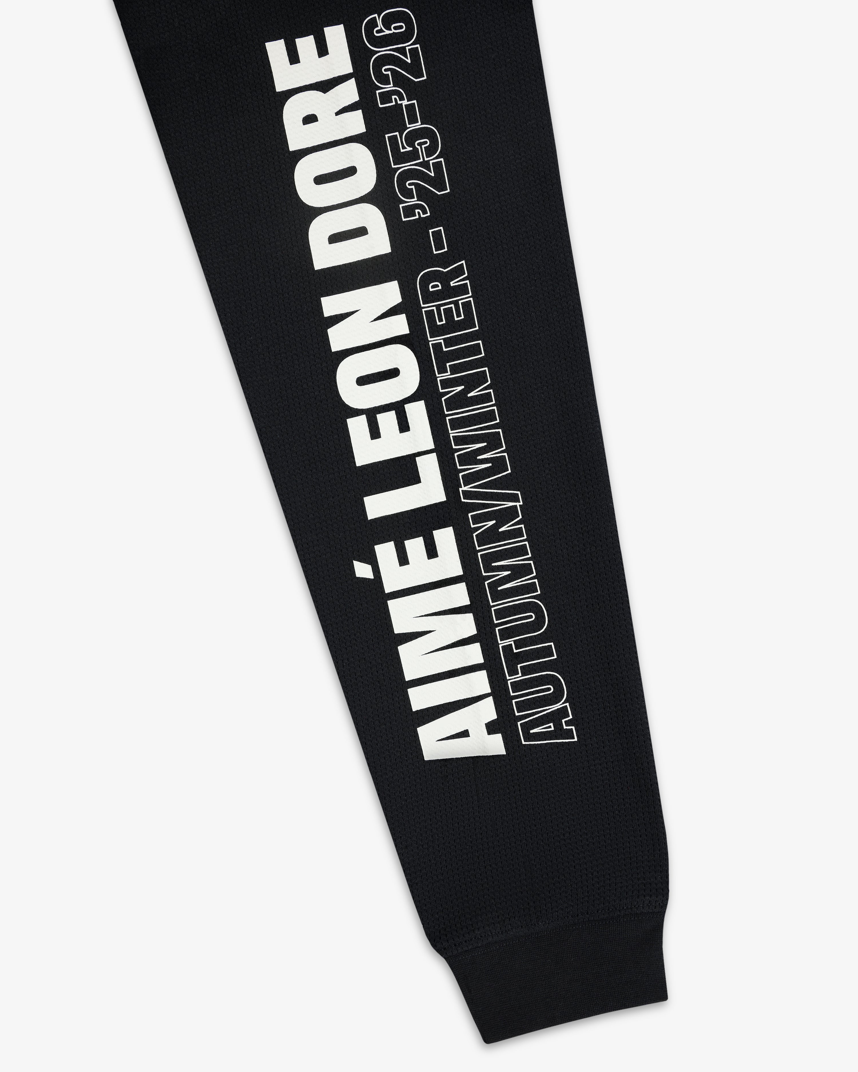 Black Long-Sleeve Mesh Moto Tee with “AIMÉ LEON DORE AUTUMN/WINTER - 25-26” in white text running vertically.