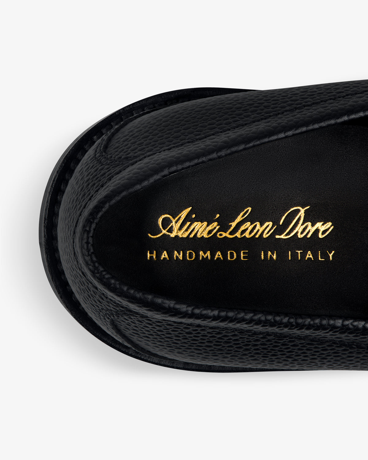 Close-up of a black Lug Sole Queens Crest Loafer with gold Aimé Leon Dore HANDMADE IN ITALY lettering on the insole.