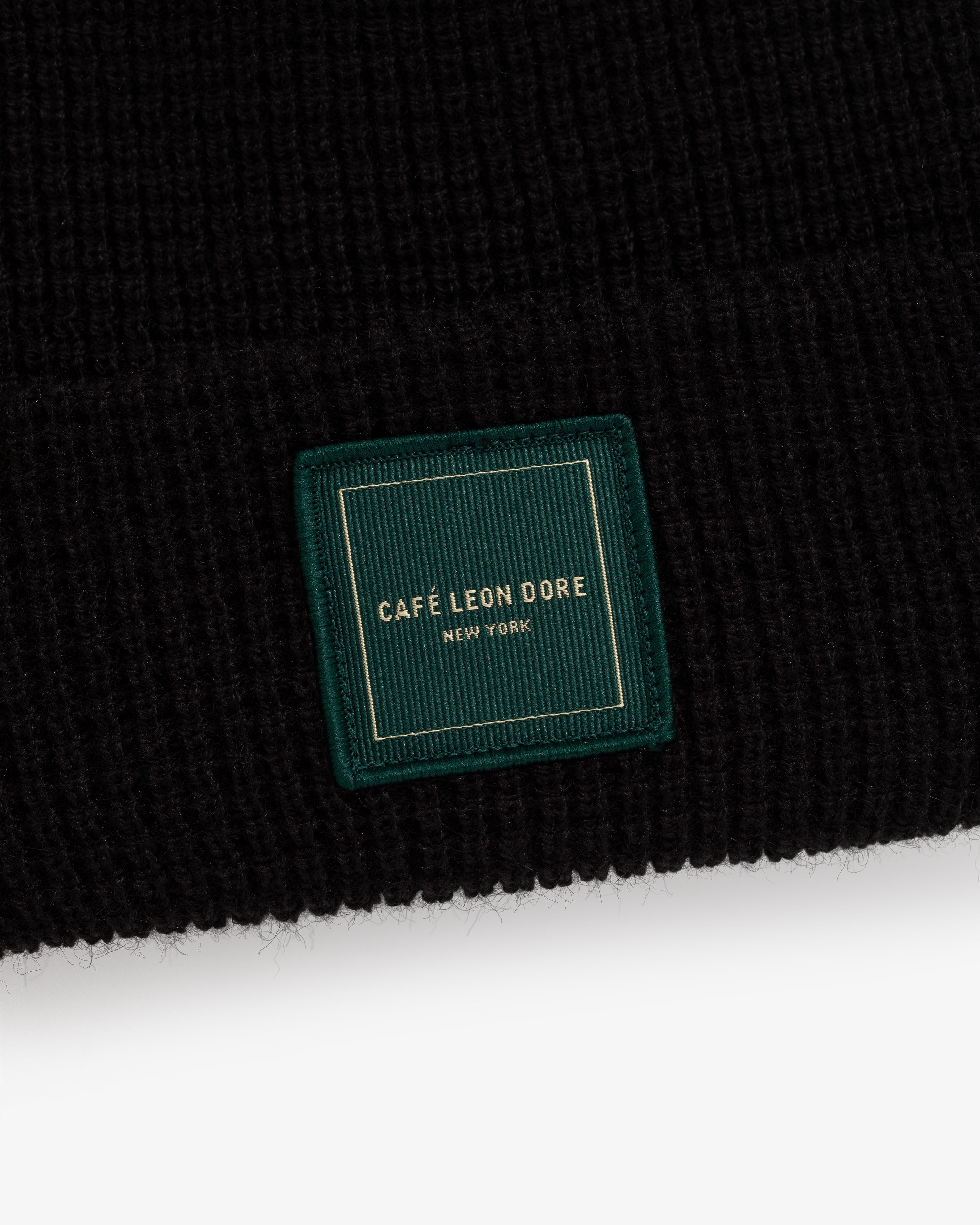 Café Leon Dore Beanie: black knit hat with a green patch, gold “CAFÉ LEON DORE NEW YORK” embroidery.