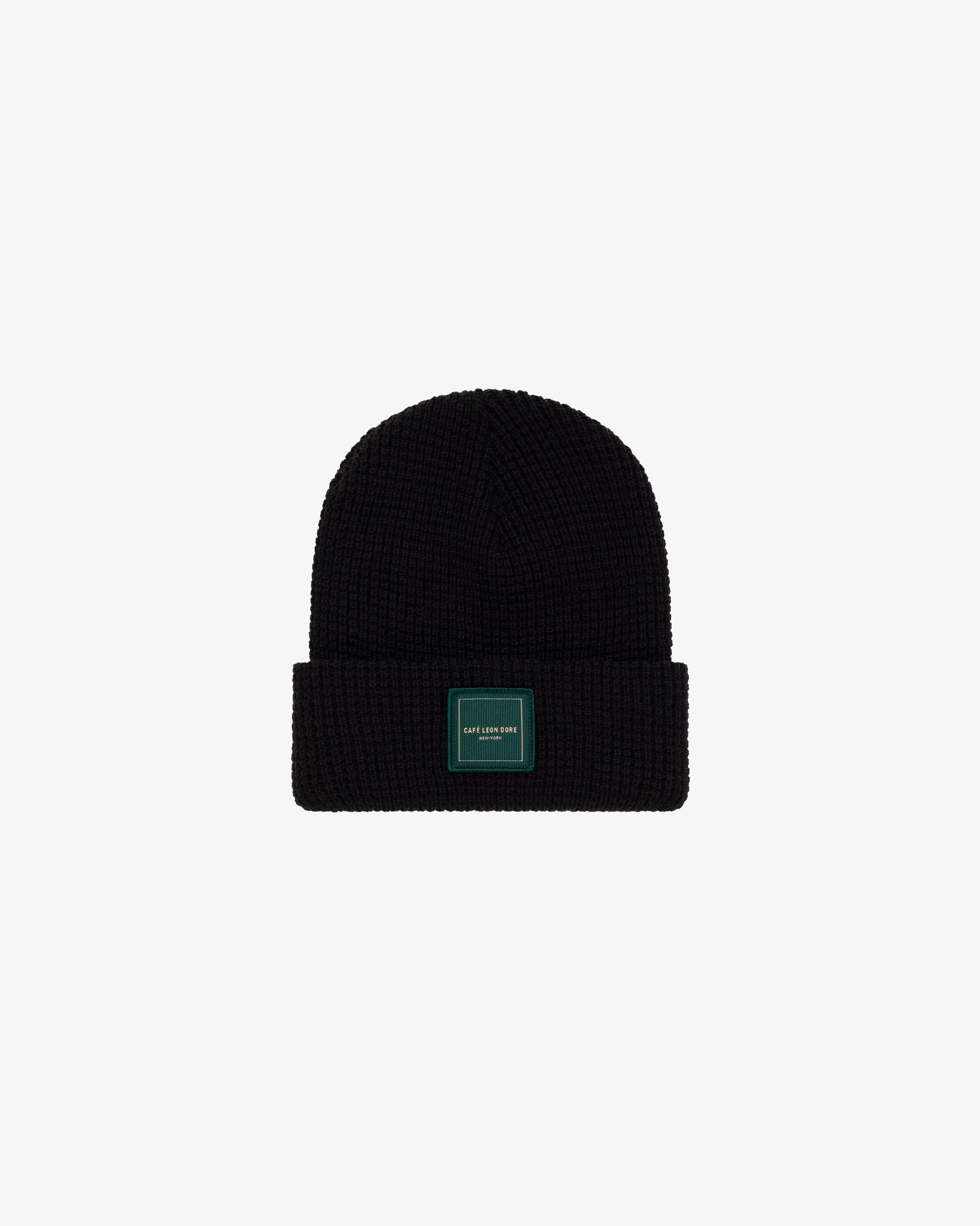 Café Leon Dore Beanie: black knit with folded brim and rectangular green patch, shown on a white background.