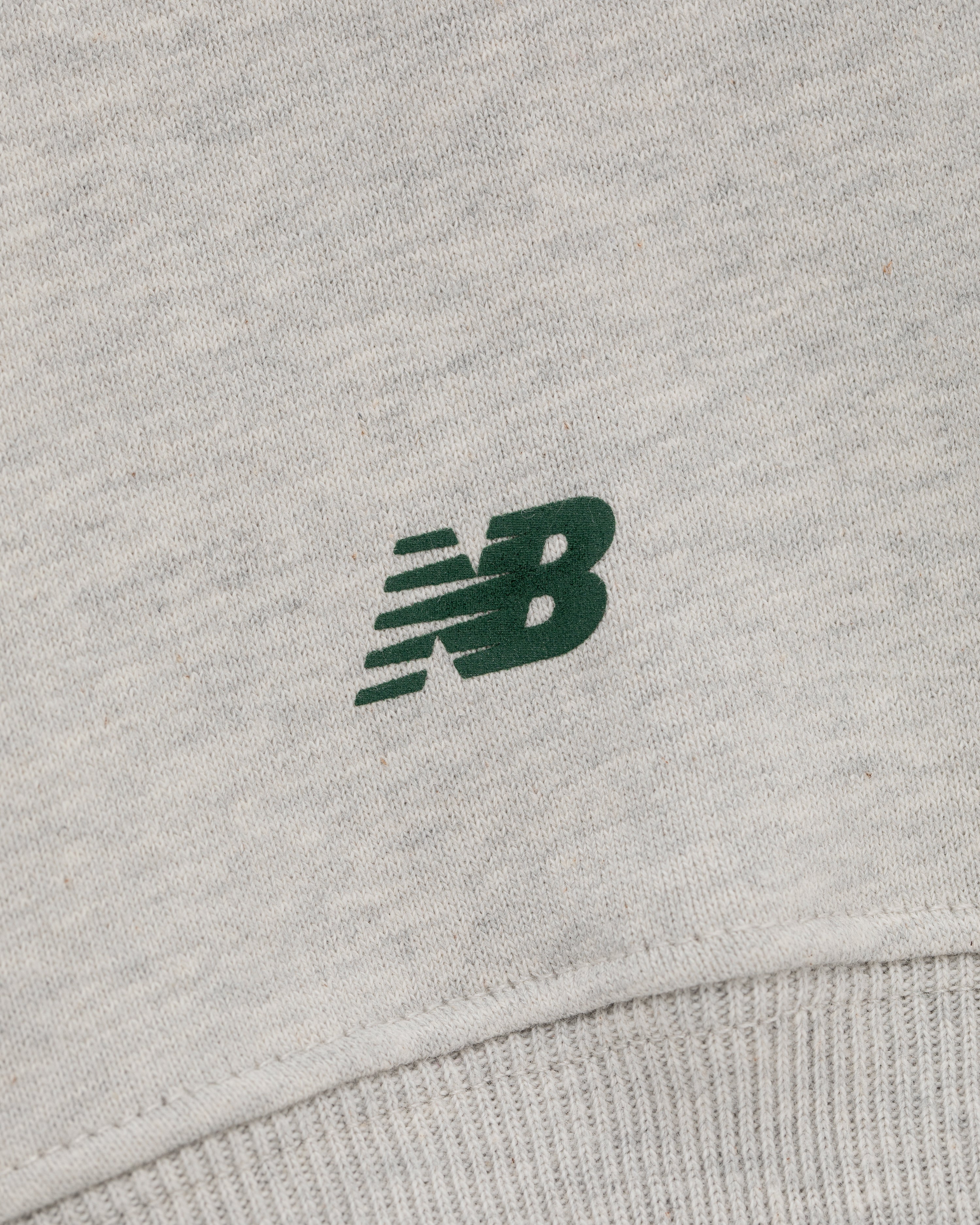 Close-up of a green New Balance logo on light grey ALD / New Balance SONNY NY IFTB Crewneck Sweatshirt.