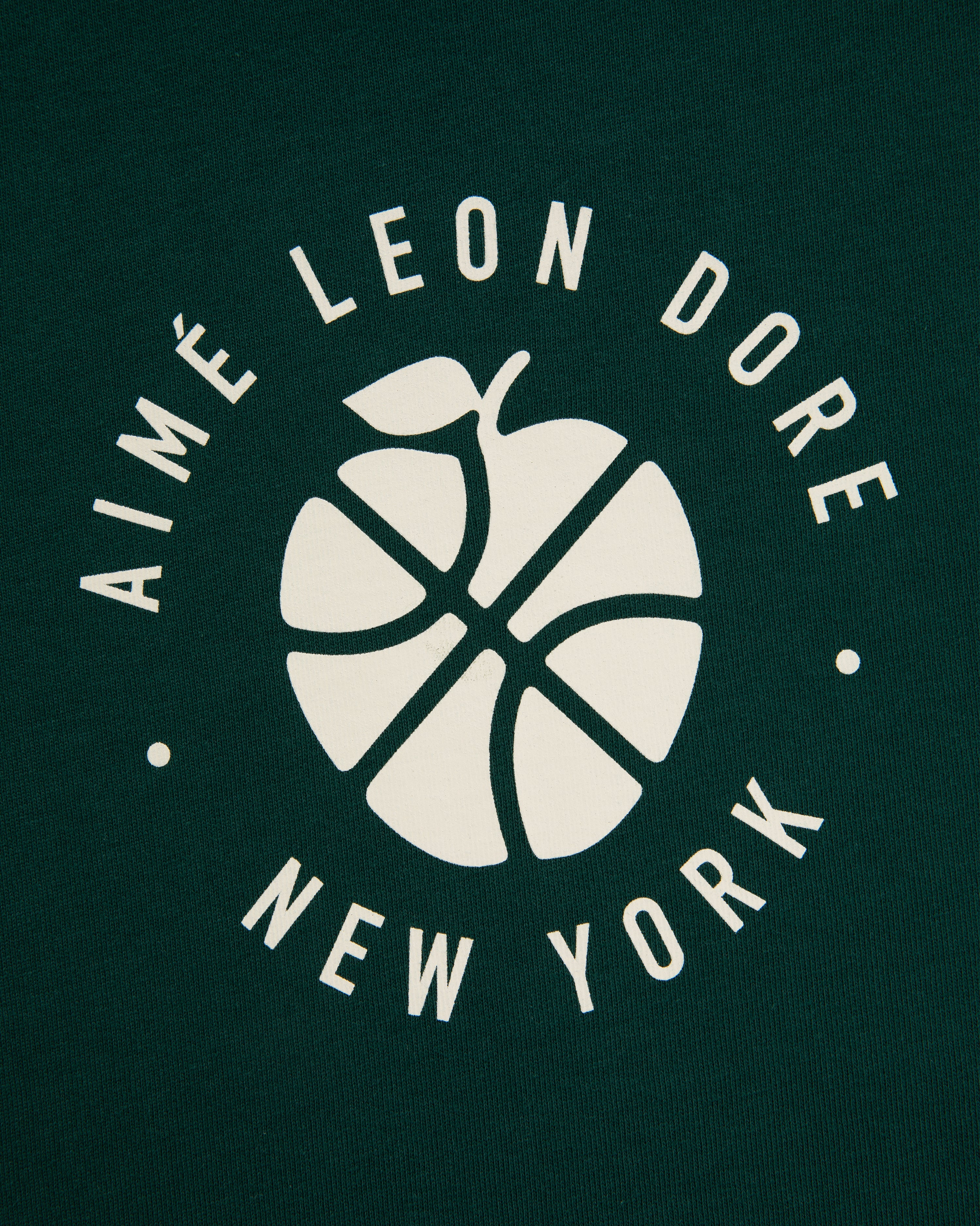 White basketball-apple logo and "AIMÉ LEON DORE NEW YORK" on dark green ALD / New Balance SONNY NY Long-Sleeve Tee.