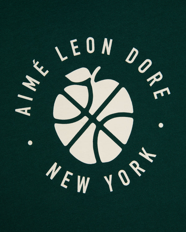 White basketball-apple logo and "AIMÉ LEON DORE NEW YORK" on dark green ALD / New Balance SONNY NY Long-Sleeve Tee.