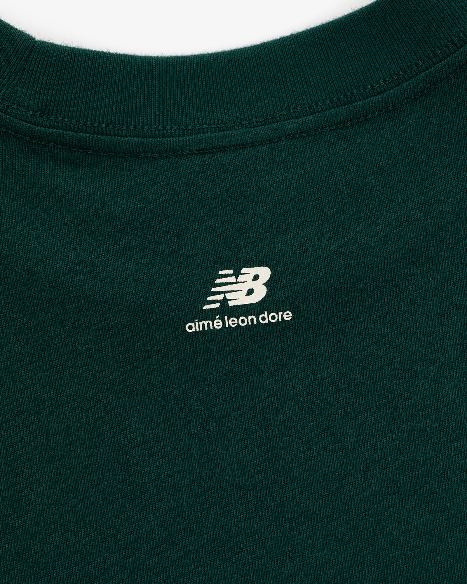 Close-up of the ALD / New Balance SONNY NY Long-Sleeve Tee in green with white logos printed below the collar on back.