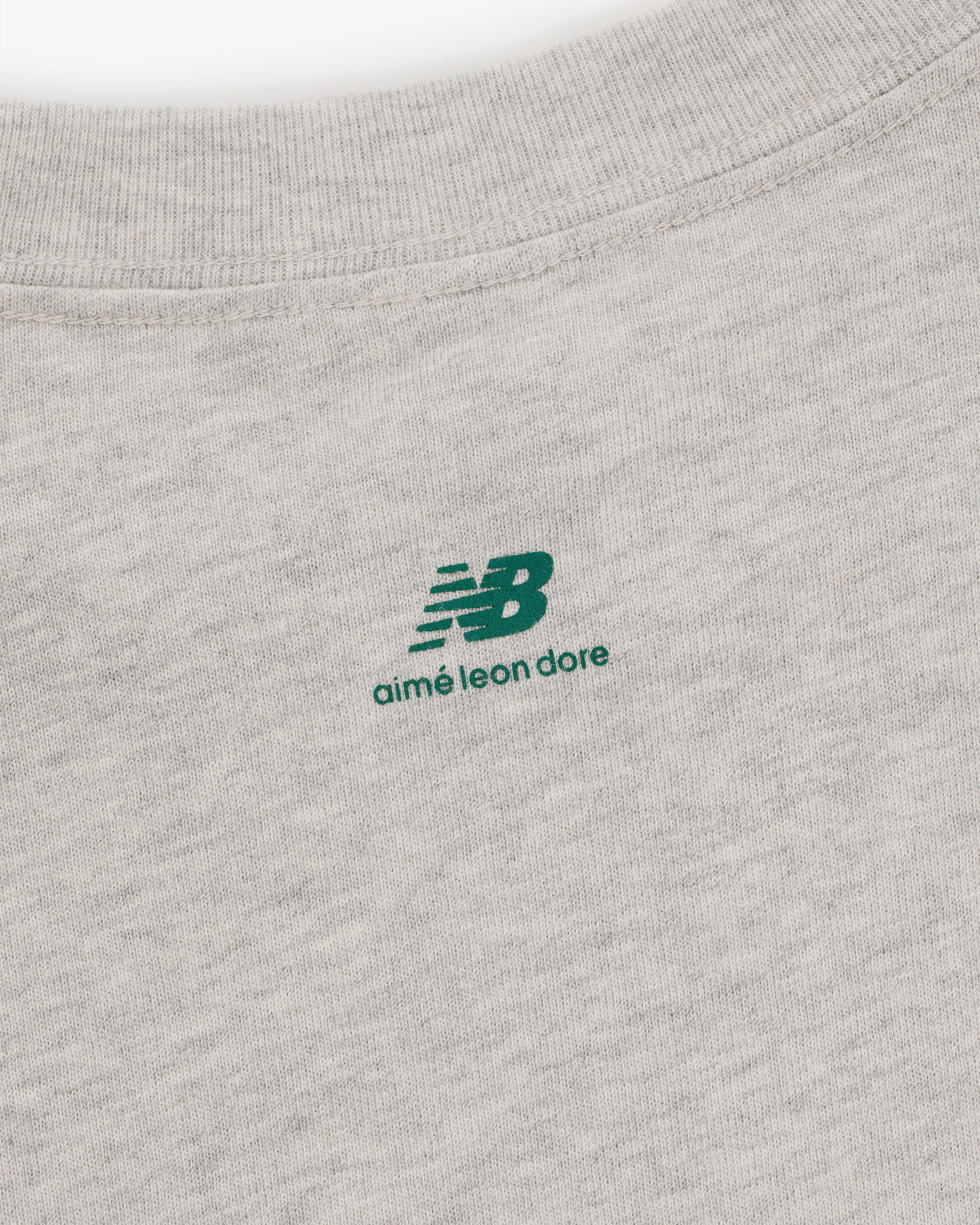 Close-up of the ALD / New Balance SONNY NY Long-Sleeve Tee with a green logo printed near the collar.