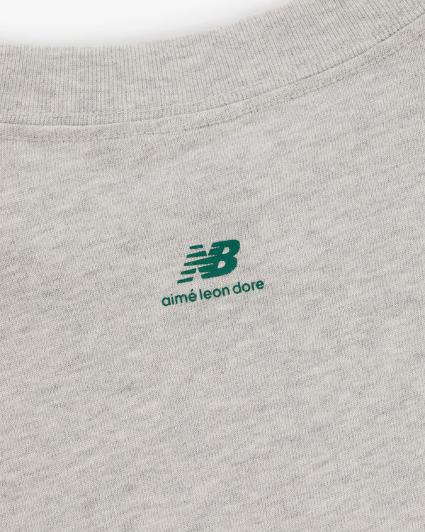 Close-up of the ALD / New Balance SONNY NY Long-Sleeve Tee with a green logo printed near the collar.