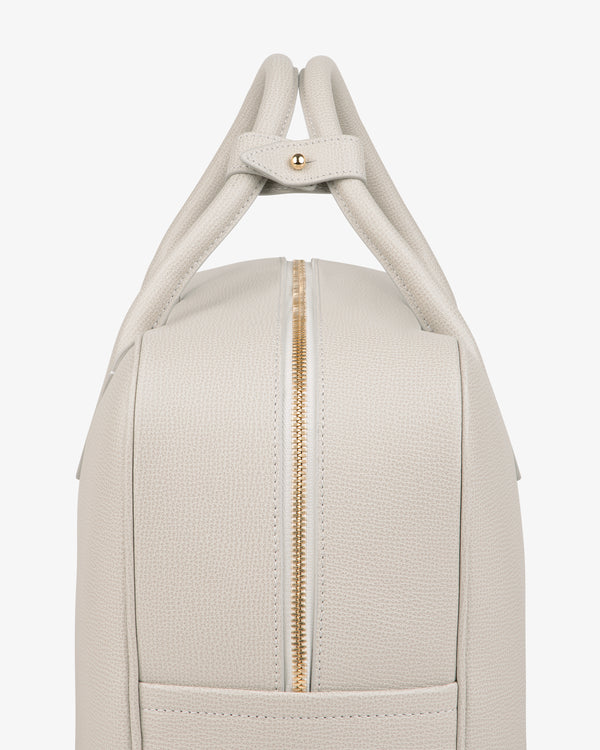 Side view of the Full Grain Leather Briefcase Duffle in light beige textured leather with gold zipper and double handles.