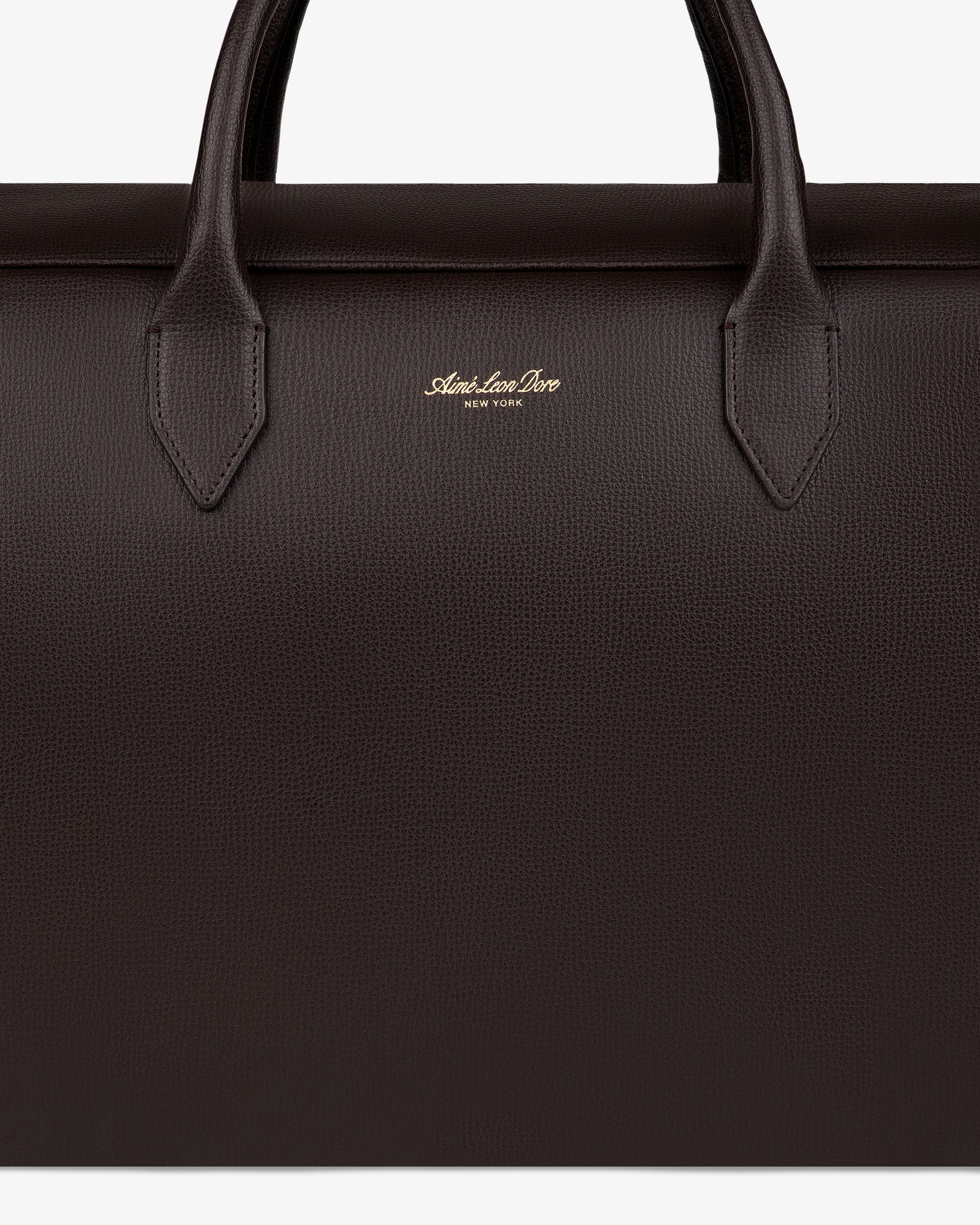 Close-up of a dark brown Full Grain Leather Briefcase Duffle with two handles and gold Mark Cross New York logo.