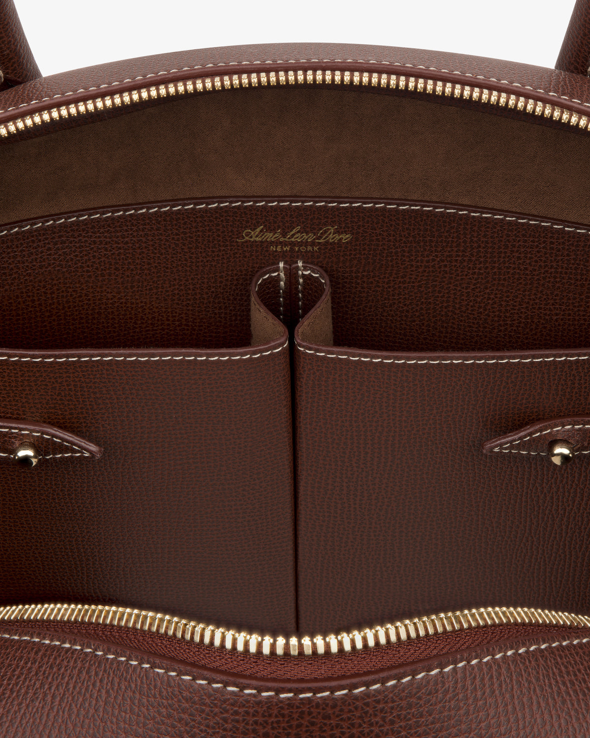 Close-up of the Full Grain Leather Crescent Shoulder Bag, featuring gold zipper, two pockets, and white stitching inside.