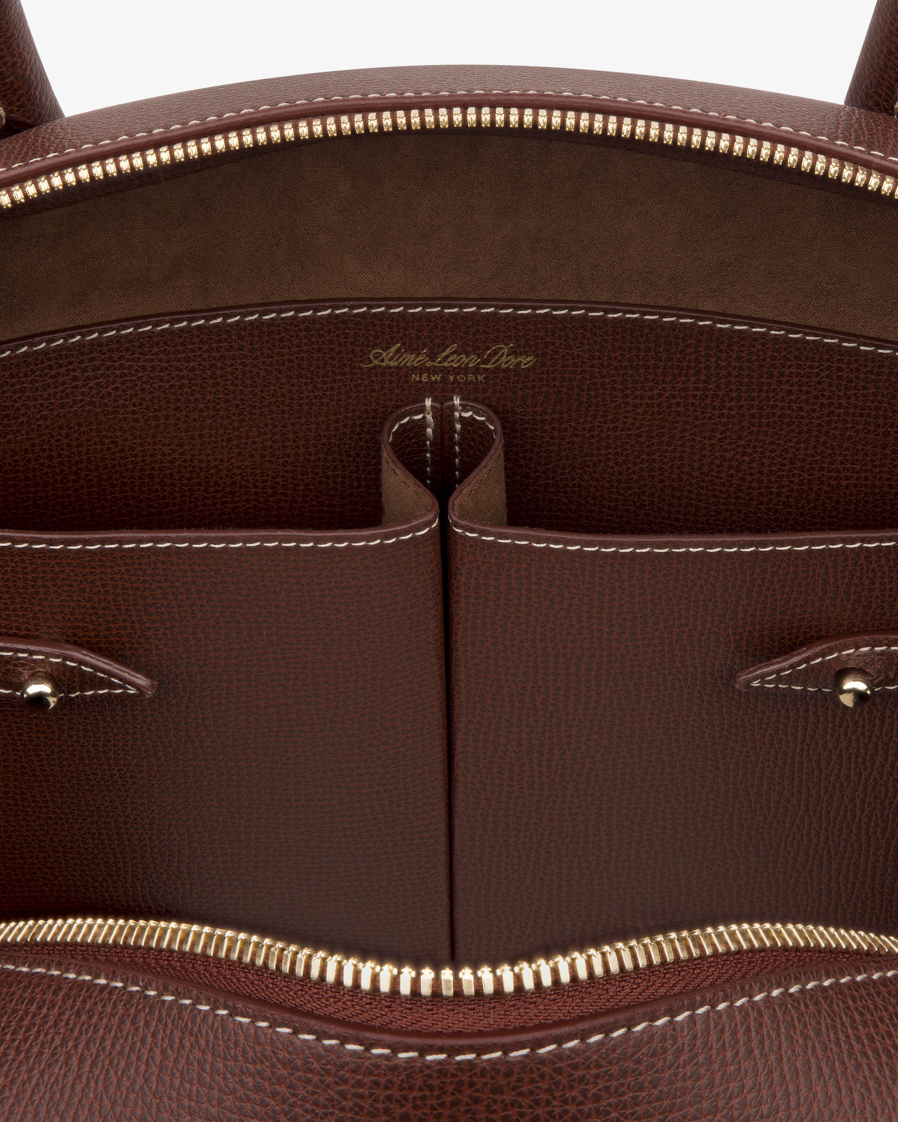 Close-up of the Full Grain Leather Crescent Shoulder Bag, featuring gold zipper, two pockets, and white stitching inside.