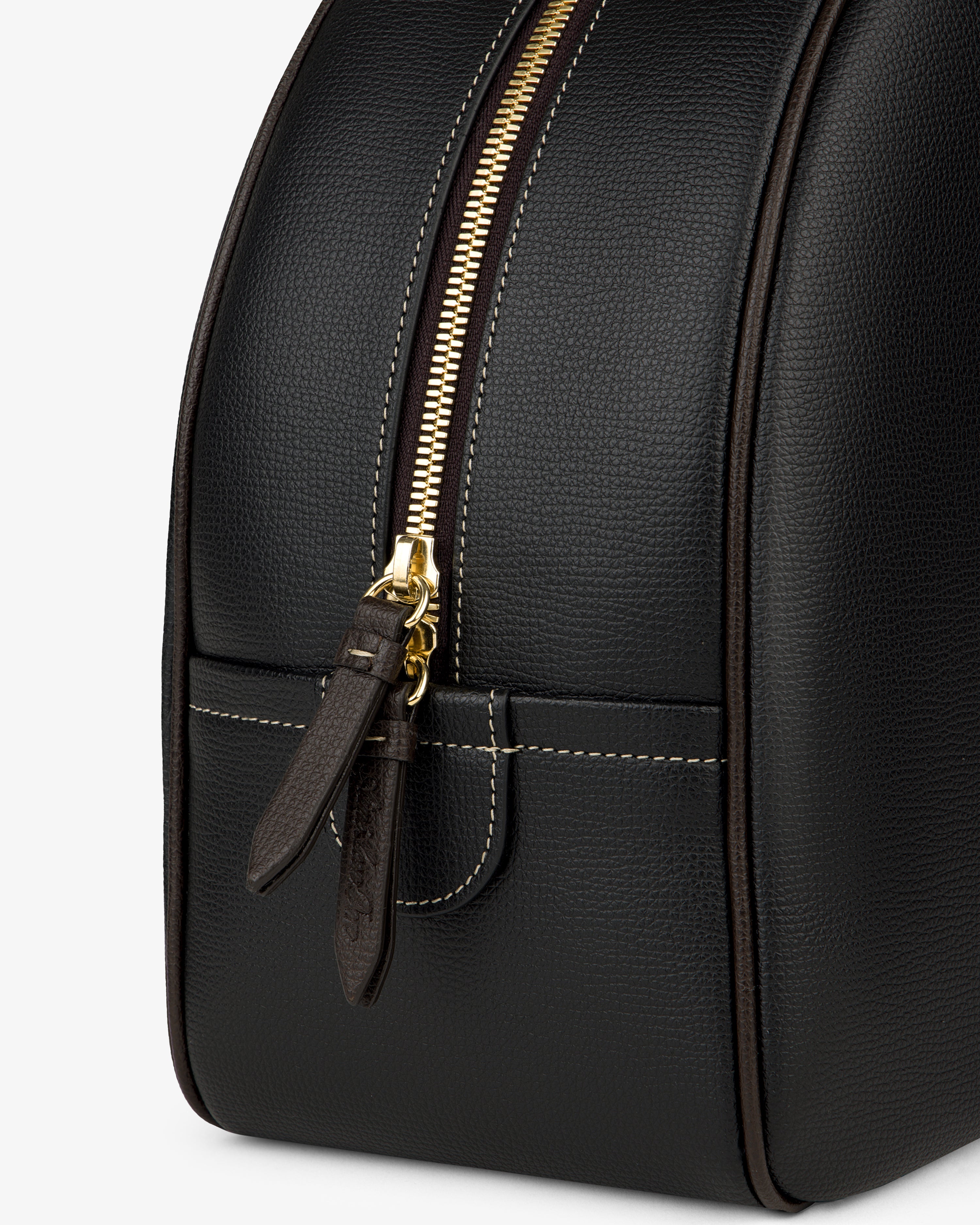 Close-up of the Full Grain Leather Crescent Shoulder Bag in black with gold zipper, brown pull tabs, and white stitching.