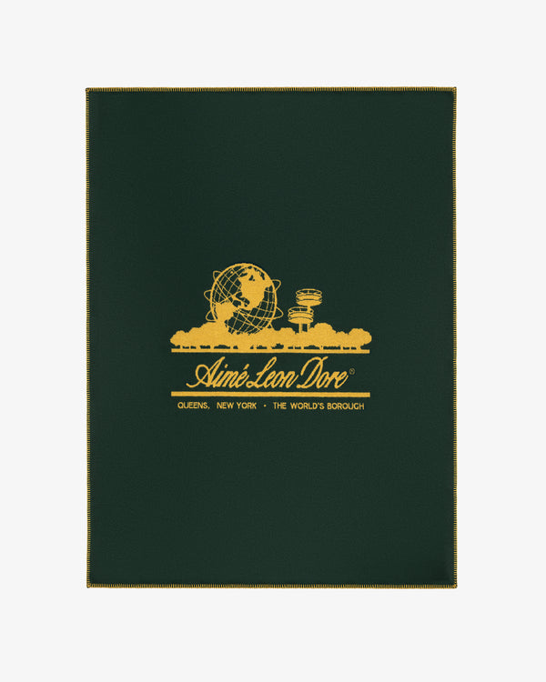 Unisphere Wool Blanket in dark green with gold Unisphere, buildings, and Aimé Leon Dore branding with location details.