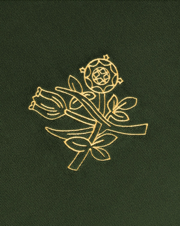 Queens Crest Throw Pillow with gold embroidered rose and floral design on dark green fabric.