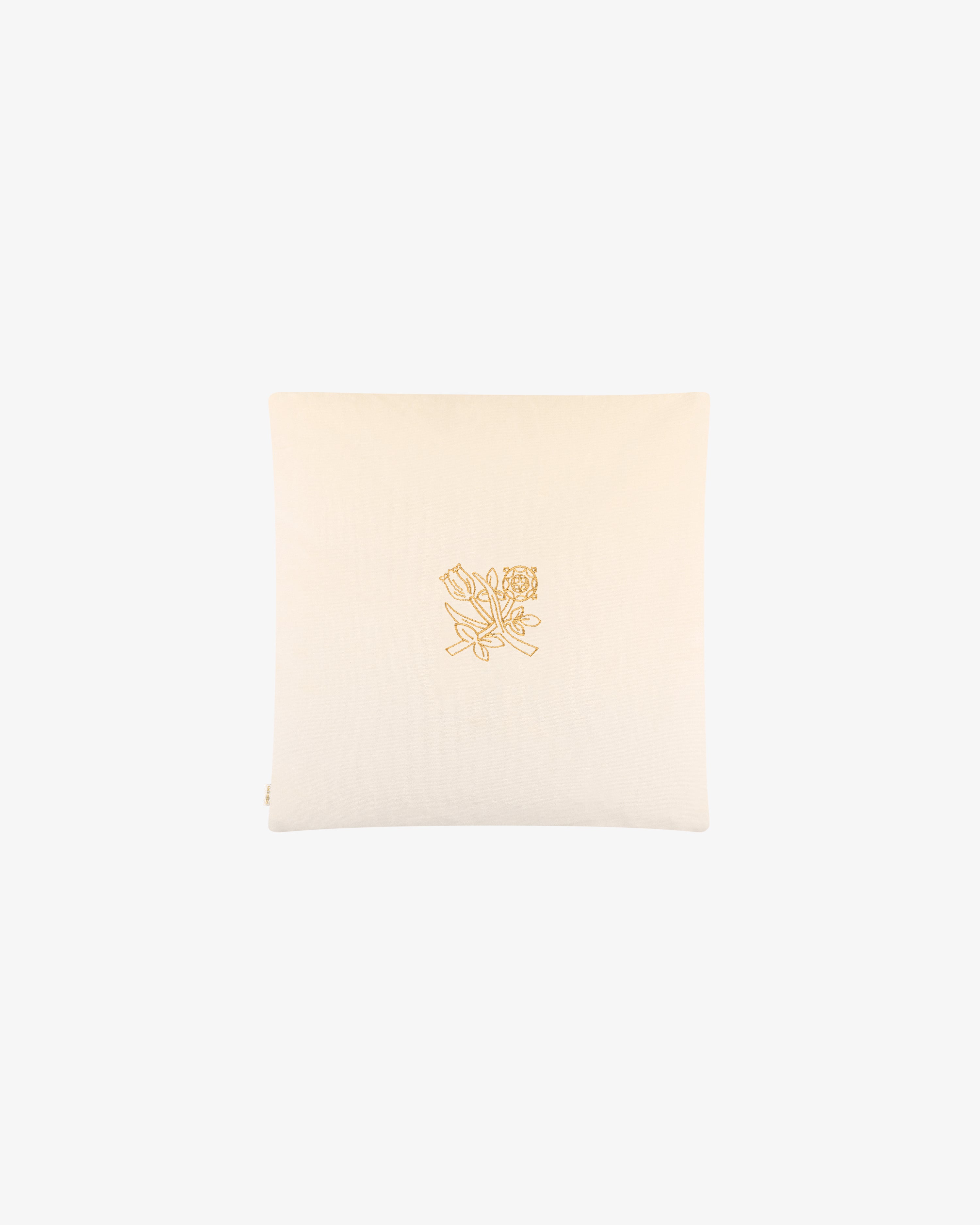 The Queens Crest Throw Pillow is cream-colored with a yellow embroidered floral line drawing in the center.