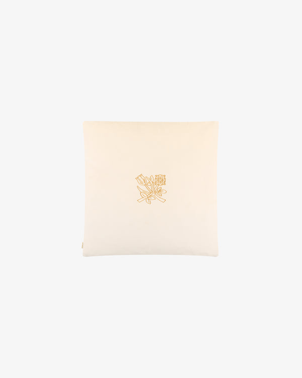 The Queens Crest Throw Pillow is cream-colored with a yellow embroidered floral line drawing in the center.