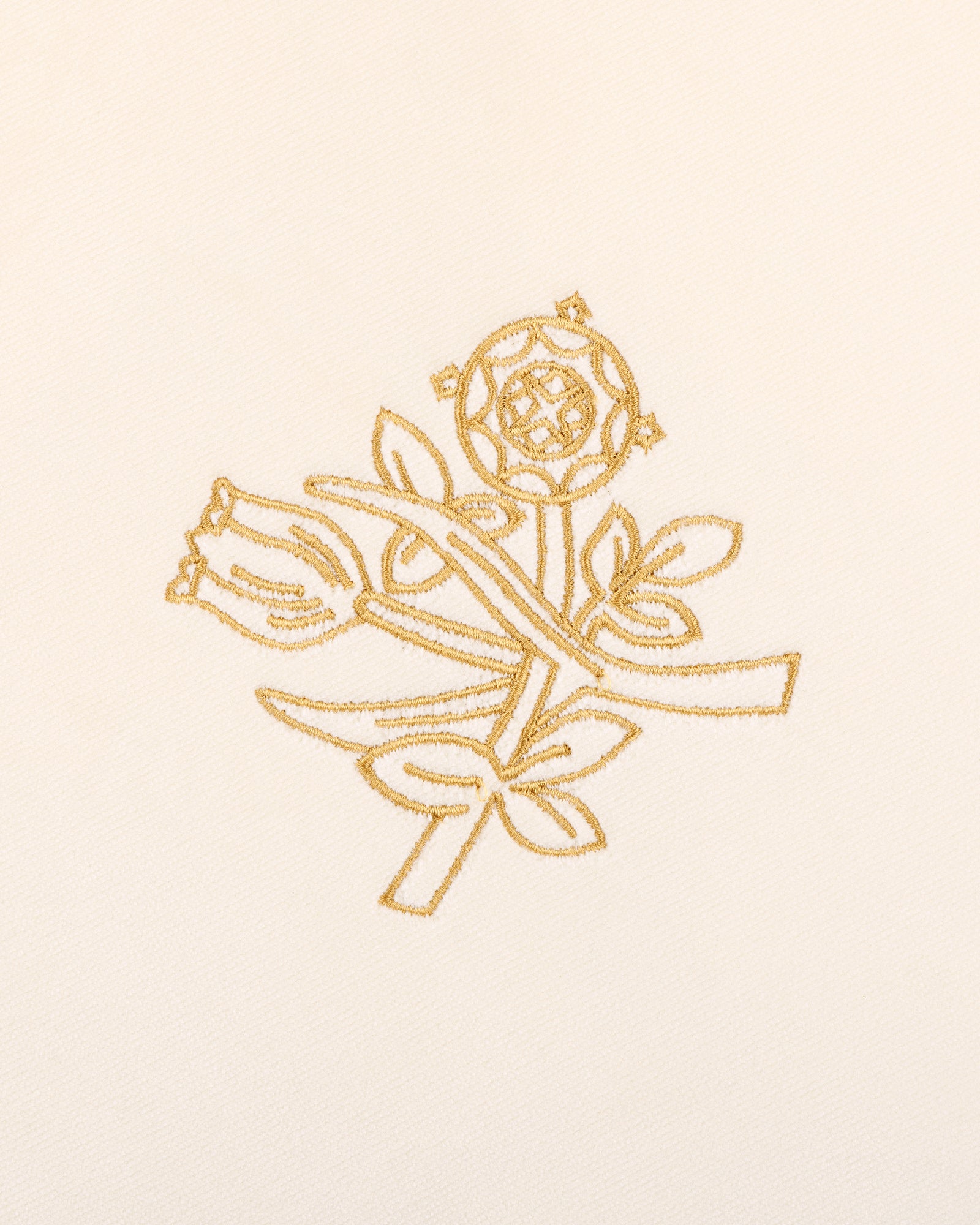 Queens Crest Throw Pillow features gold embroidered roses and buds with leaves on a cream fabric background.