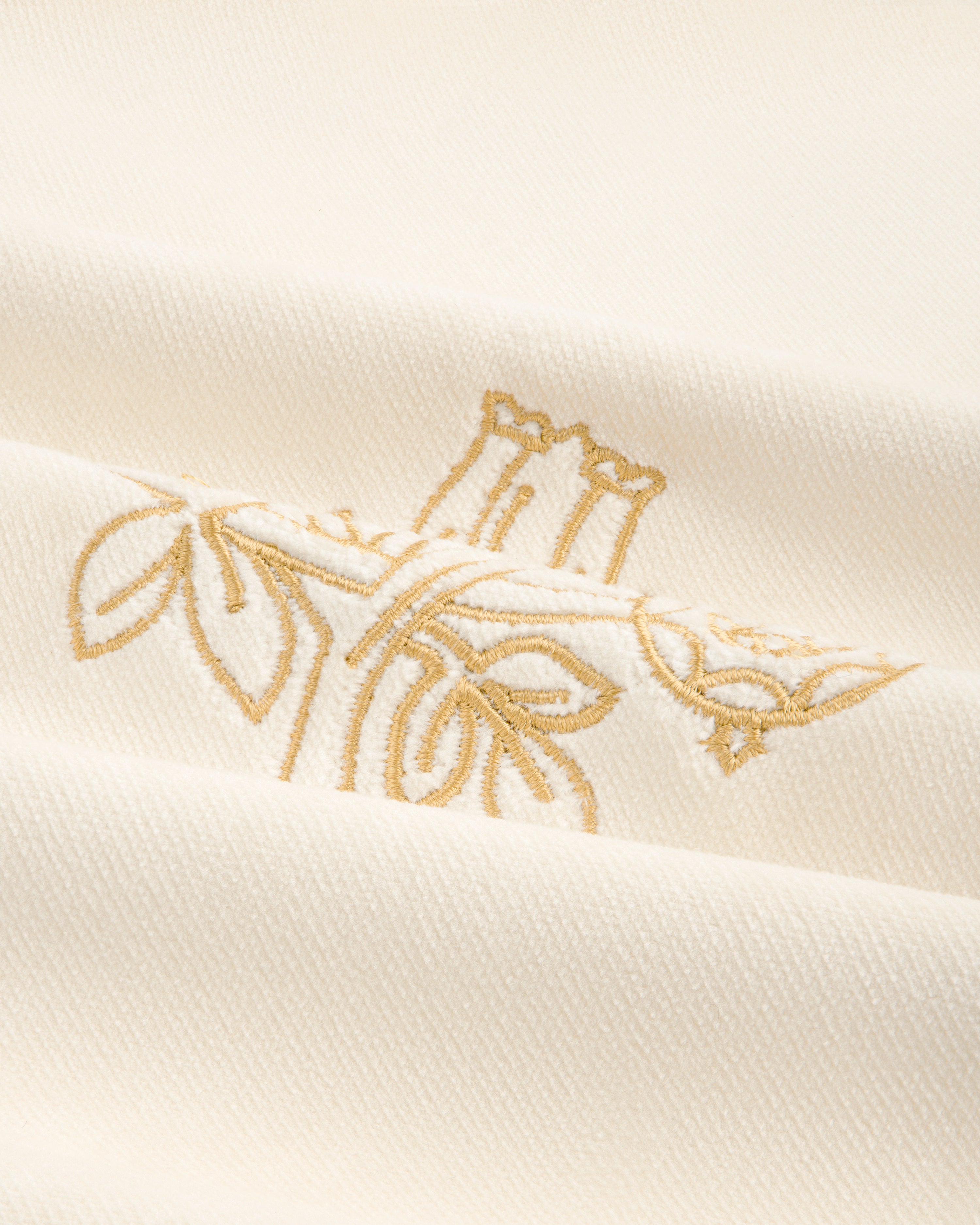 Queens Crest Throw Pillow: White fabric with gold floral embroidery and a soft, textured finish.