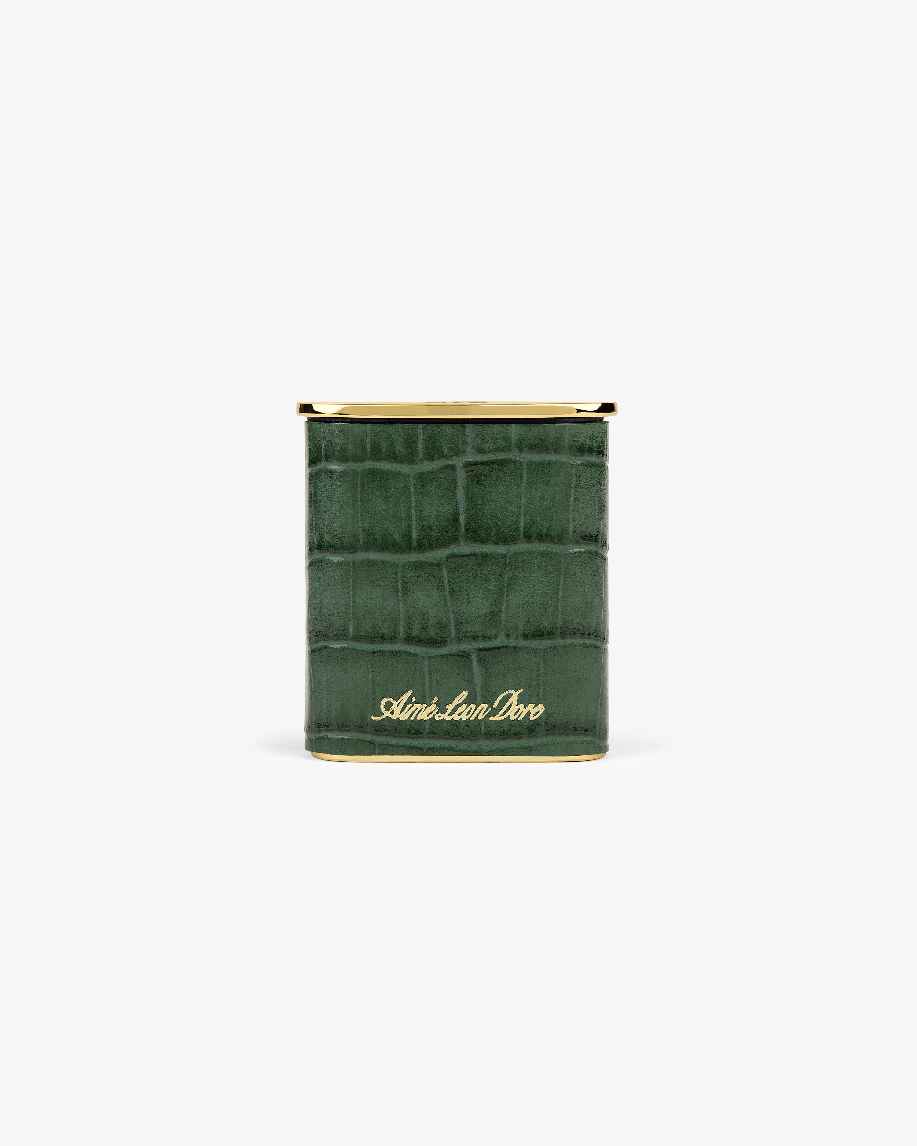 A green faux-crocodile Queens Crest Croc Portable Ashtray with gold trim and Aimé Leon Dore script on the front.