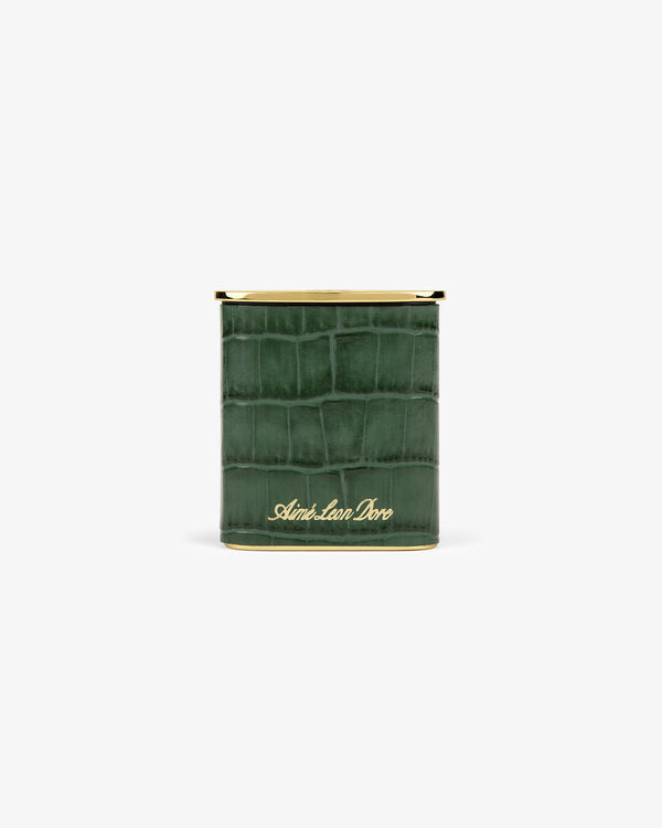 A green faux-crocodile Queens Crest Croc Portable Ashtray with gold trim and Aimé Leon Dore script on the front.