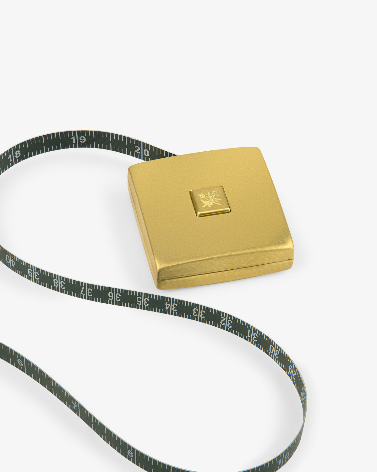 The Queens Crest Brass Tape Measure features a gold square case and a green tape, partially extended on a white background.