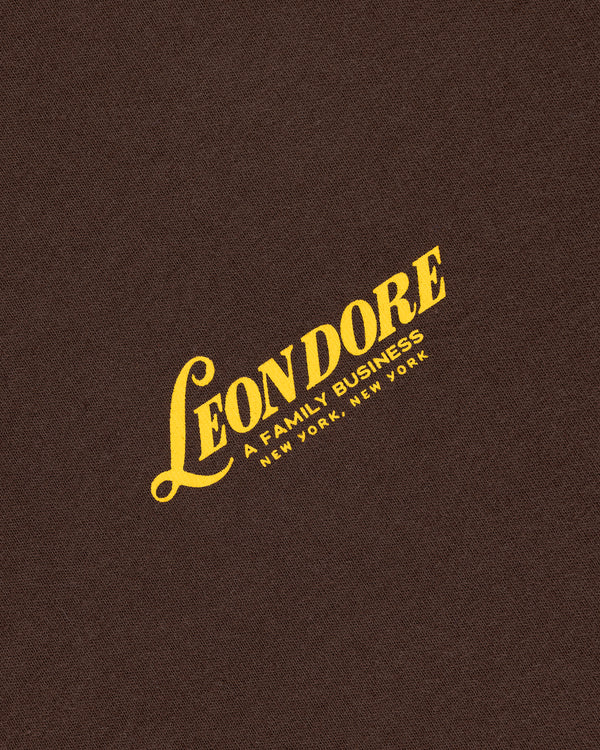 Yellow "LEON DORE, A FAMILY BUSINESS, NEW YORK, NEW YORK" text on brown textured Leon Dore Tee.